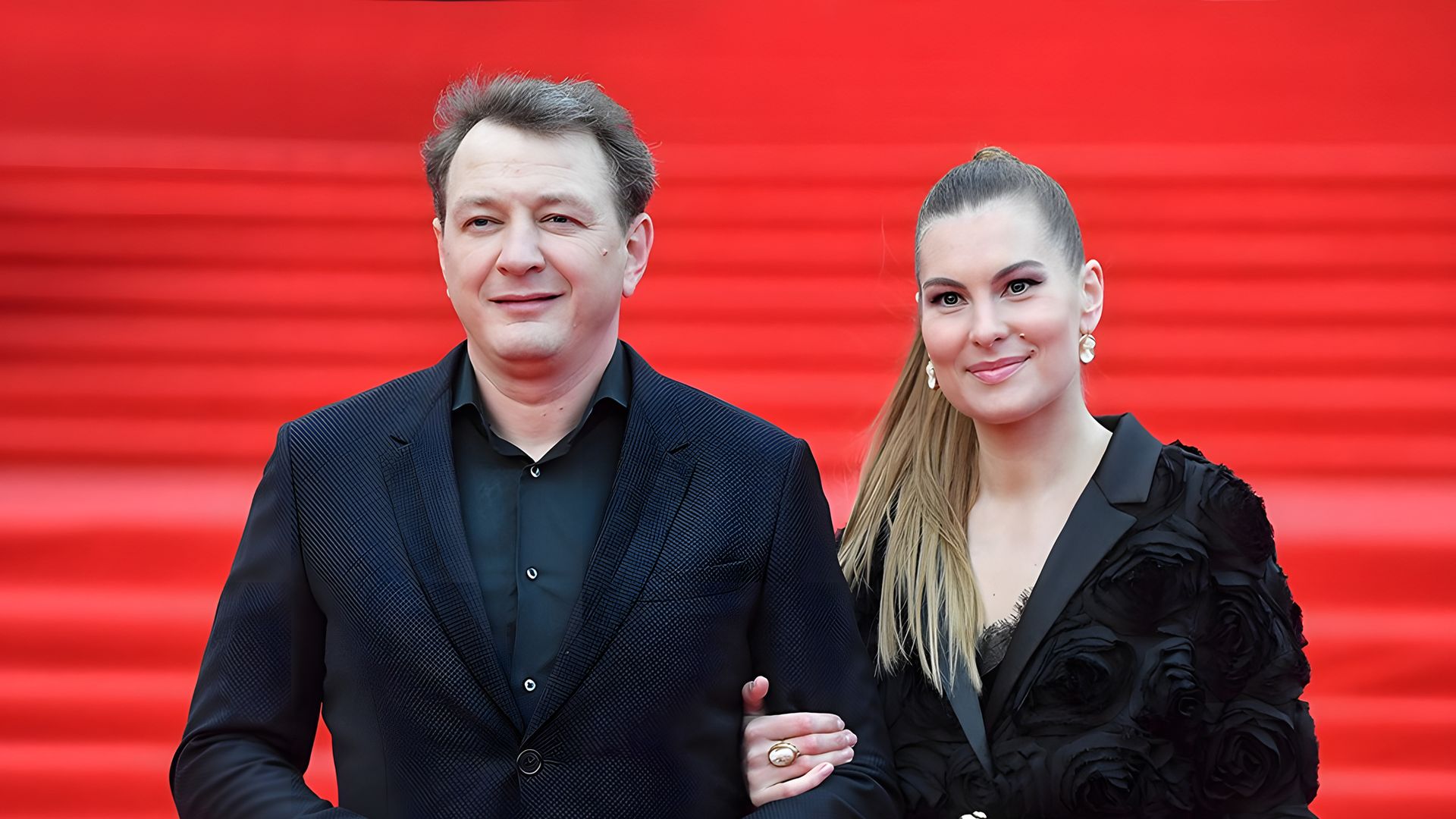 Мужчина и женщина в чёрных вечерних нарядах на красной дорожке