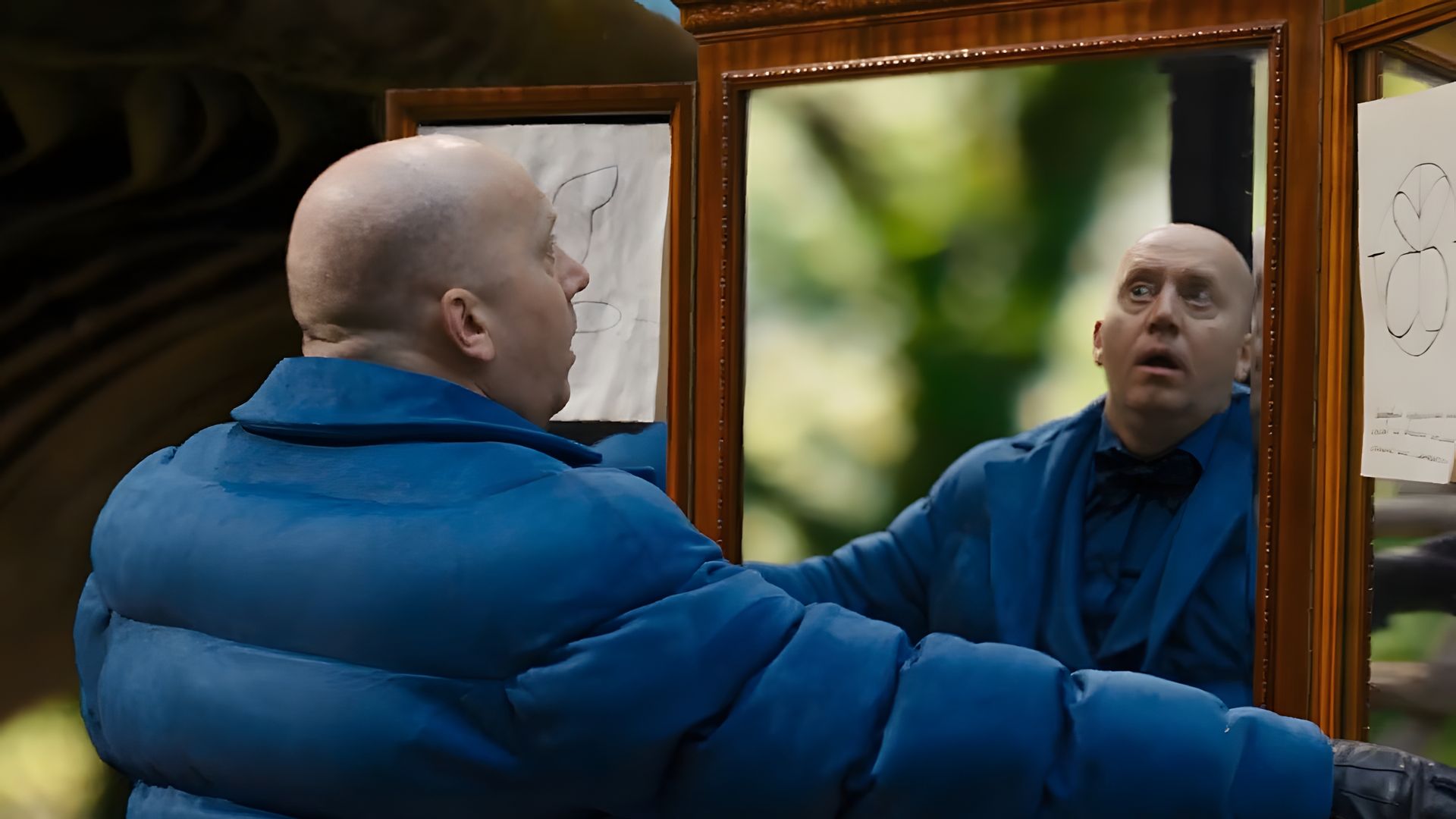 Сергей Бурунов в синей дутой куртке смотрит на себя в зеркало