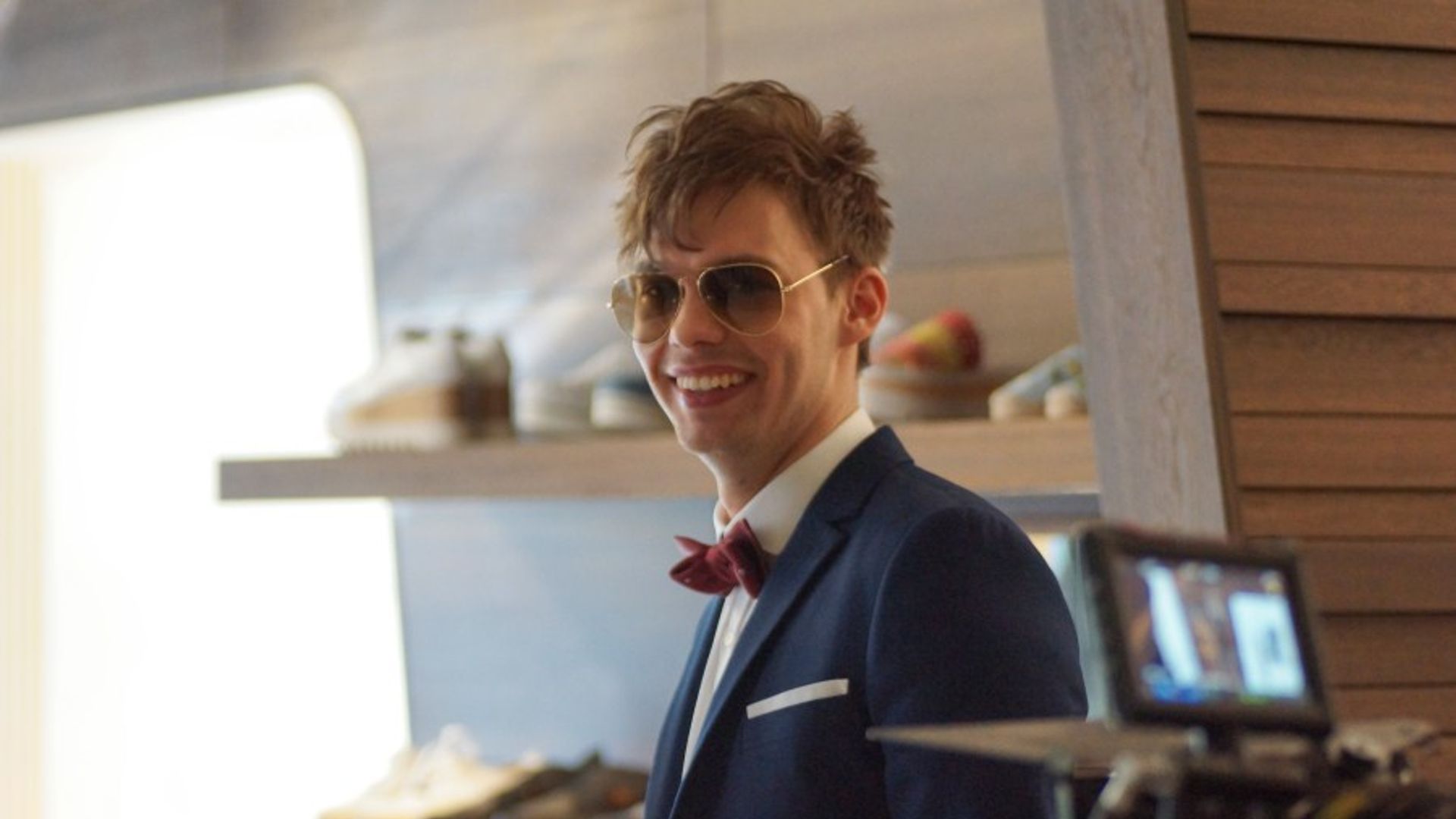 Аристарх Венес в костюме и солнечных очках улыбается