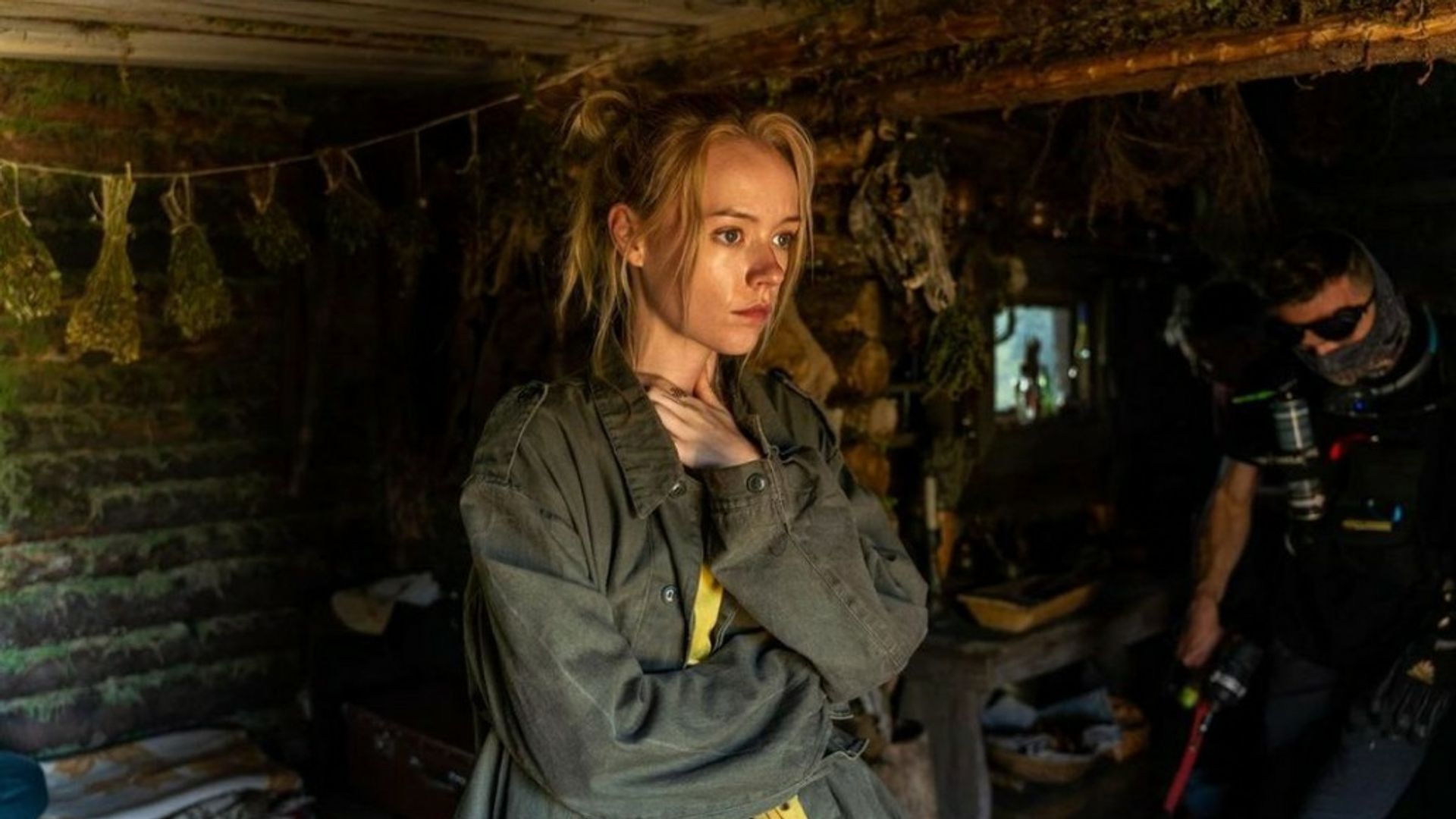 Виктория Агалакова в мешковатой одежде стоит в декорациях землянки