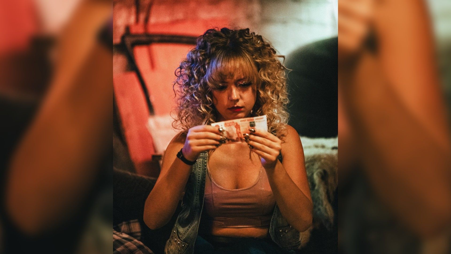 Виктория Агалакова с кудряшками смотрит на купюру в пять тысяч