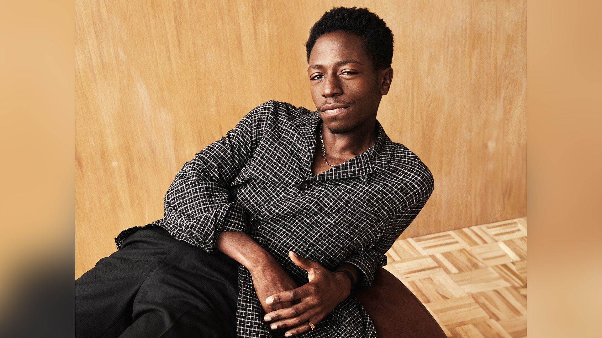 Актёр Дэвид Джонссон в рубашке в черно-белую клетку лежит, облокотившись на одну руку