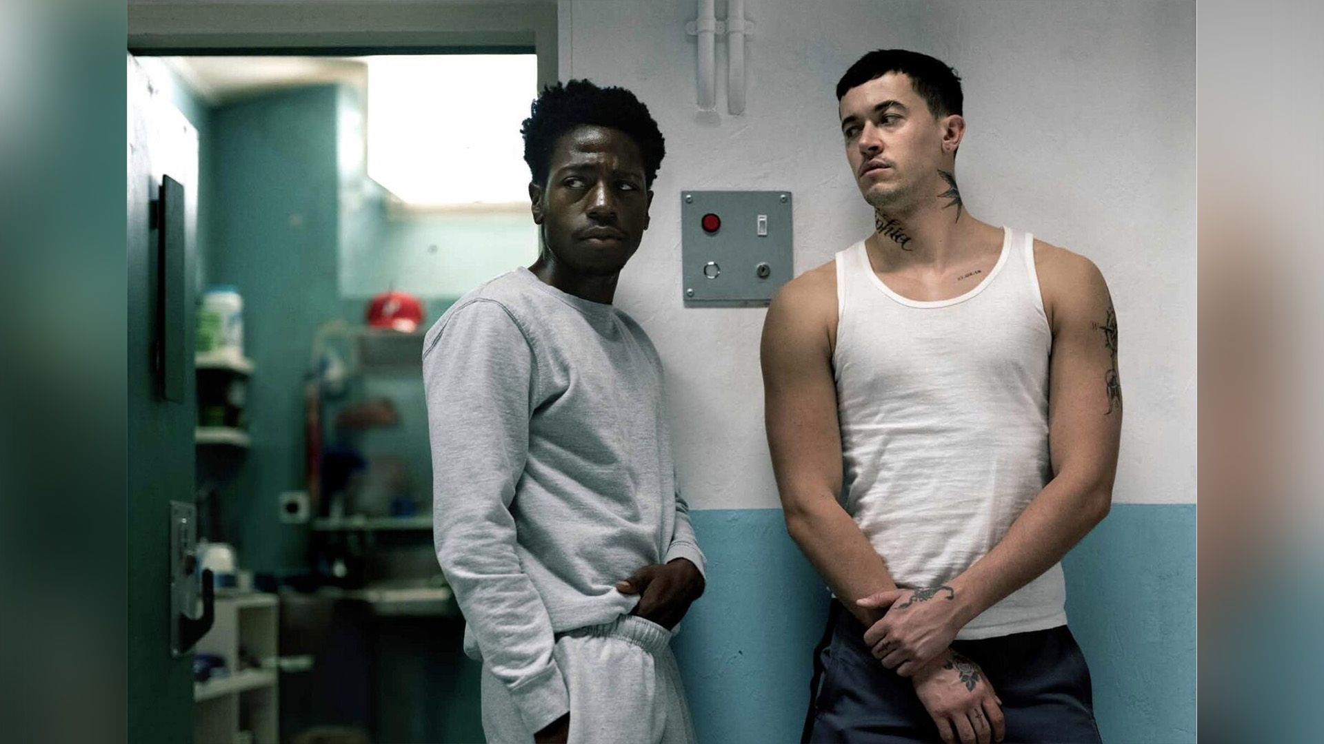 Дэвид Джонссон в сером спортивном костюме стоит у тюремной камеры рядом с высоким мужчиной в белой майке