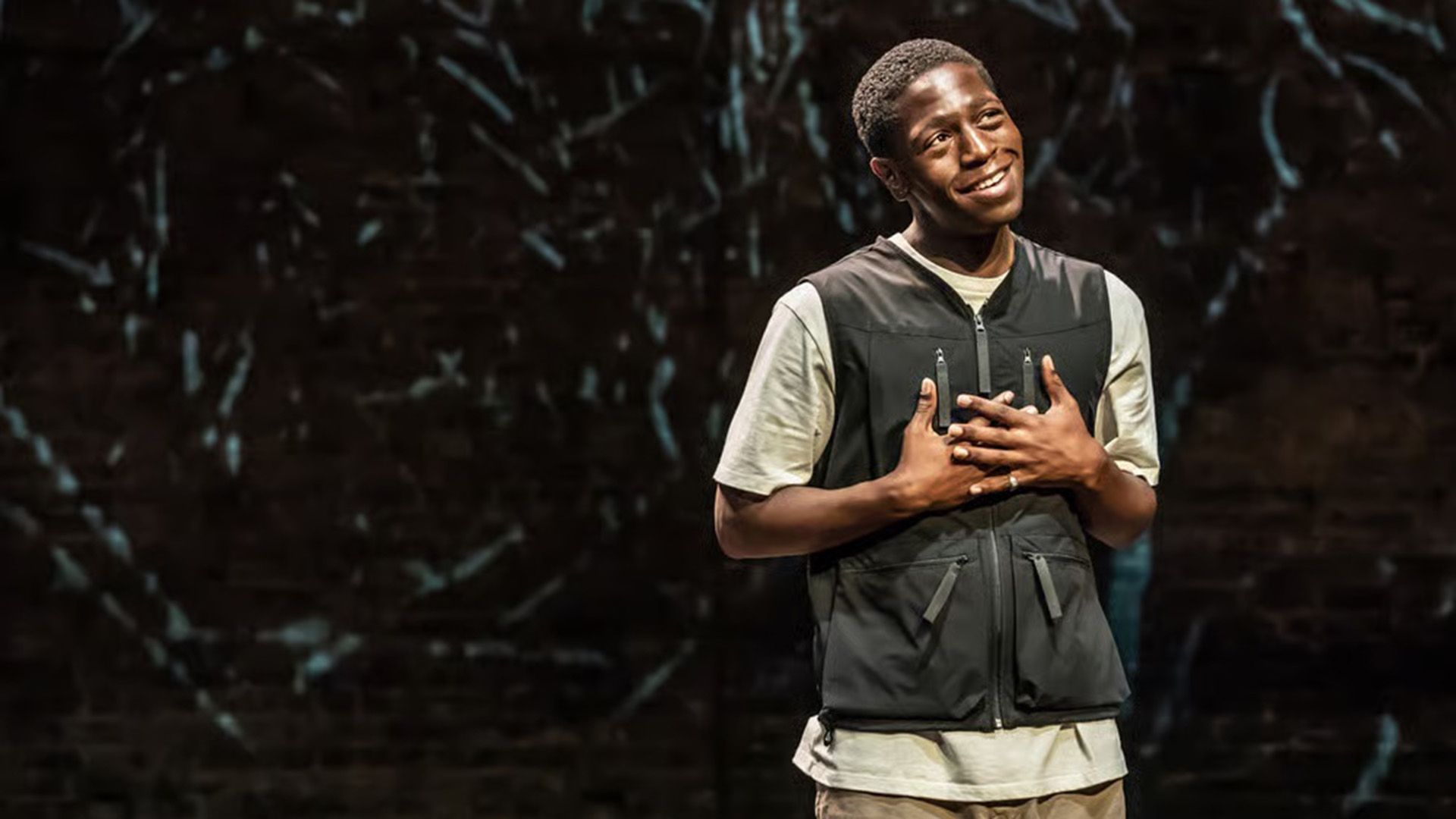 Дэвид Джонссон в белой футболке и черном жилете мечтательно смотрит вверх, сложив на груди руки