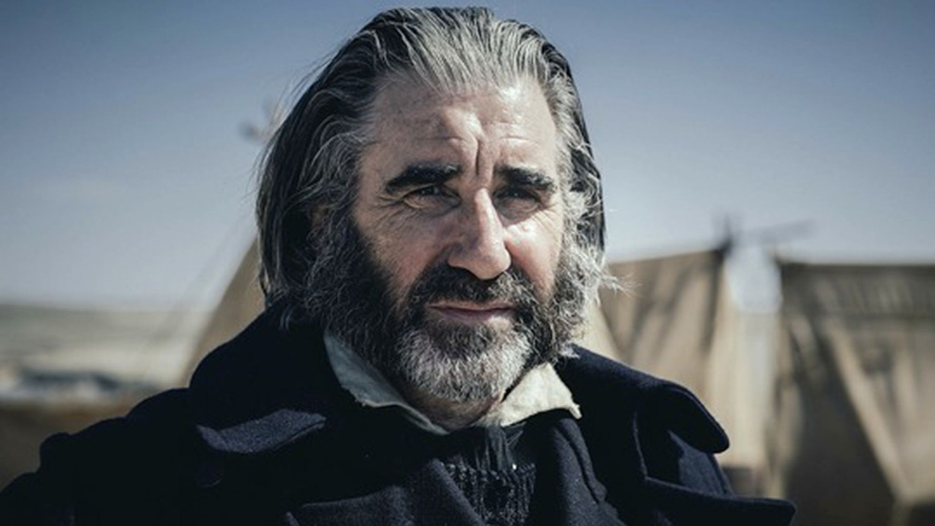 Джон Линч с седой бородой щурится на солнце