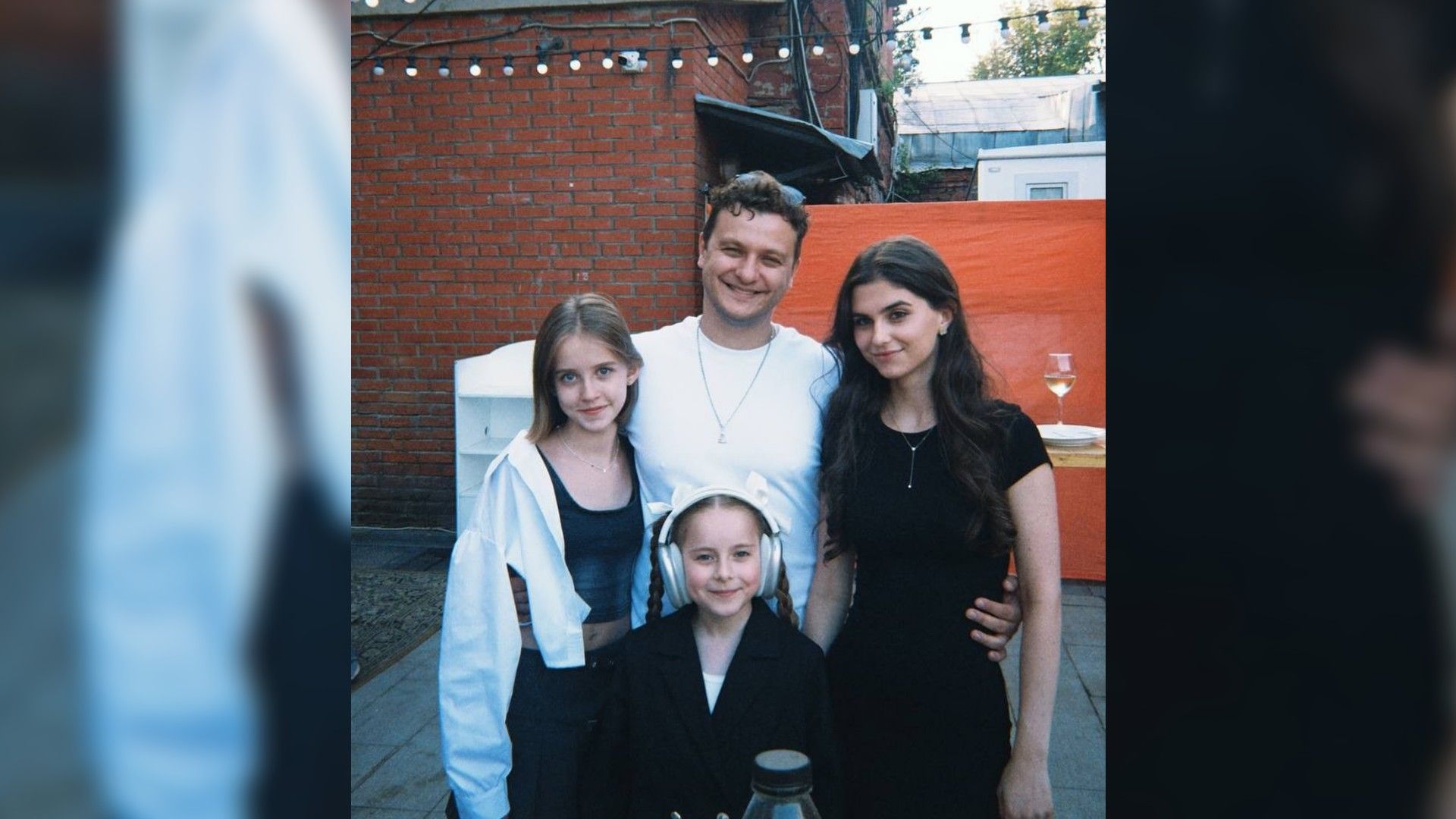 Филипп Бледный обнимает юных актрис на фоне кирпичных зданий