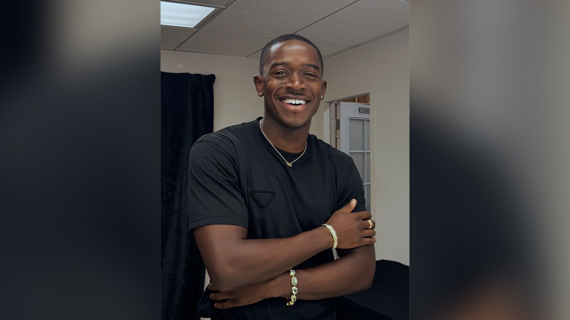 Демсон Идрис, одетый в чёрную футболку, широко улыбается