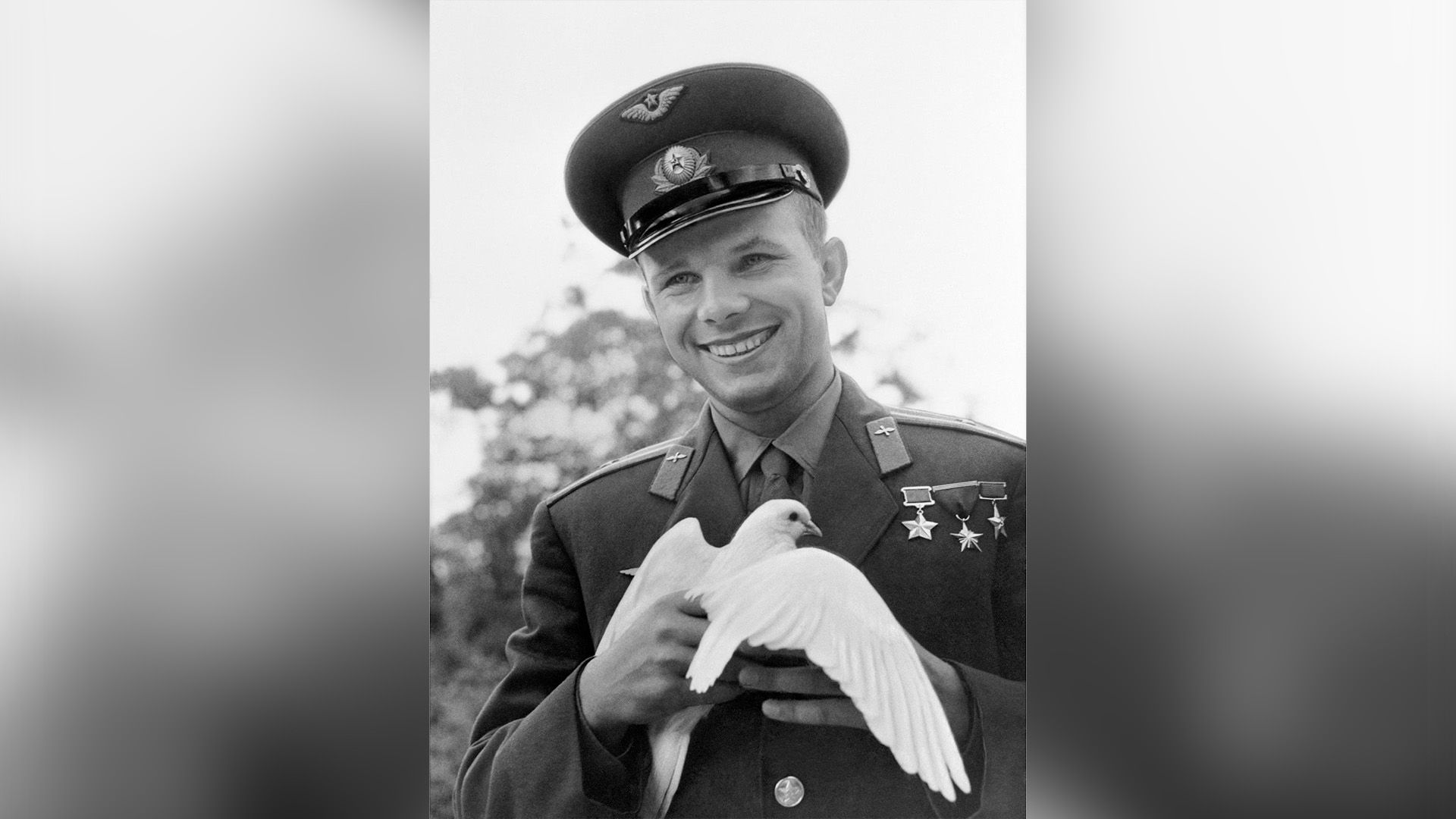 Юрий Гагарин в фуражке держит в руках белого голубя