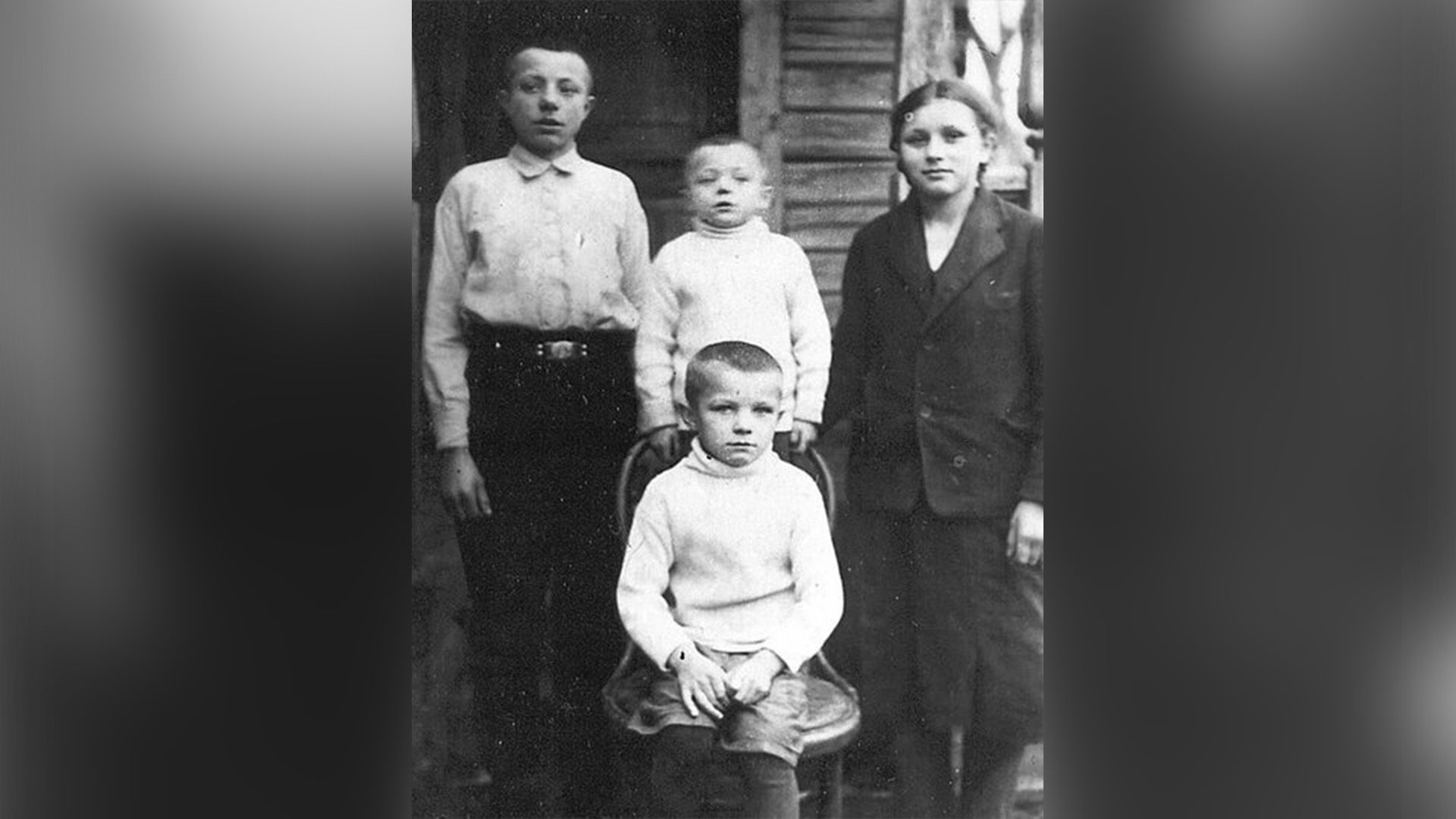 Юрий Гагарин сидит на стуле, вокруг него стоят его сестра Зоя и братья Борис и Валентин