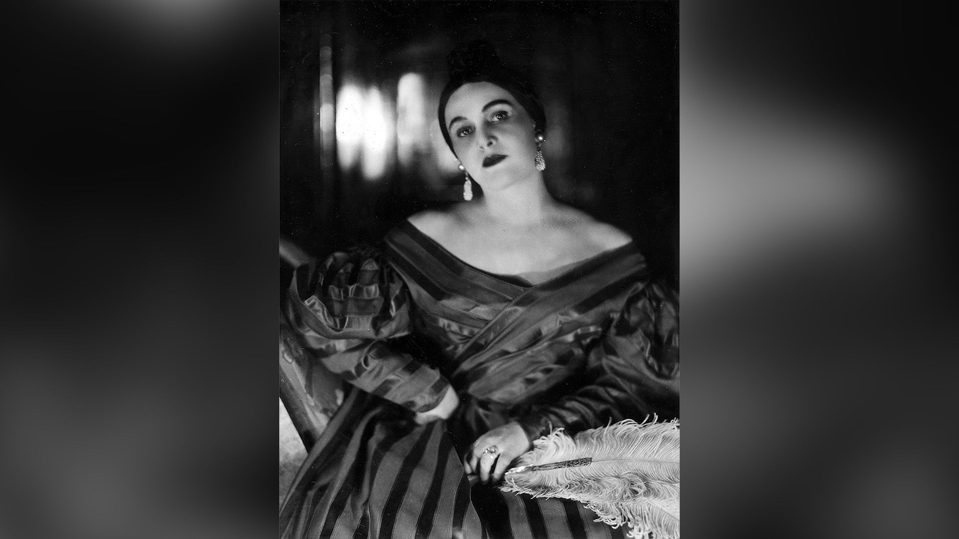 Зинаида Райх в полосатом платье и со страусиным пером в руке