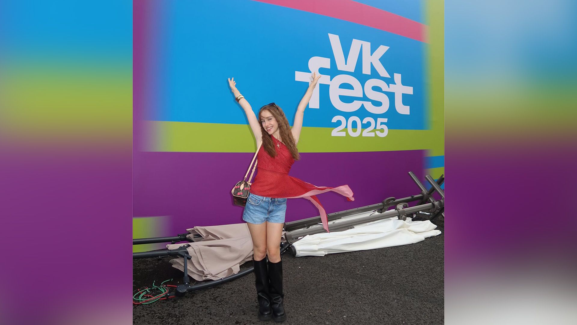 Марьяна Локель в красном топе и джинсовых шортах позирует на фоне надписи VK Fest 2025