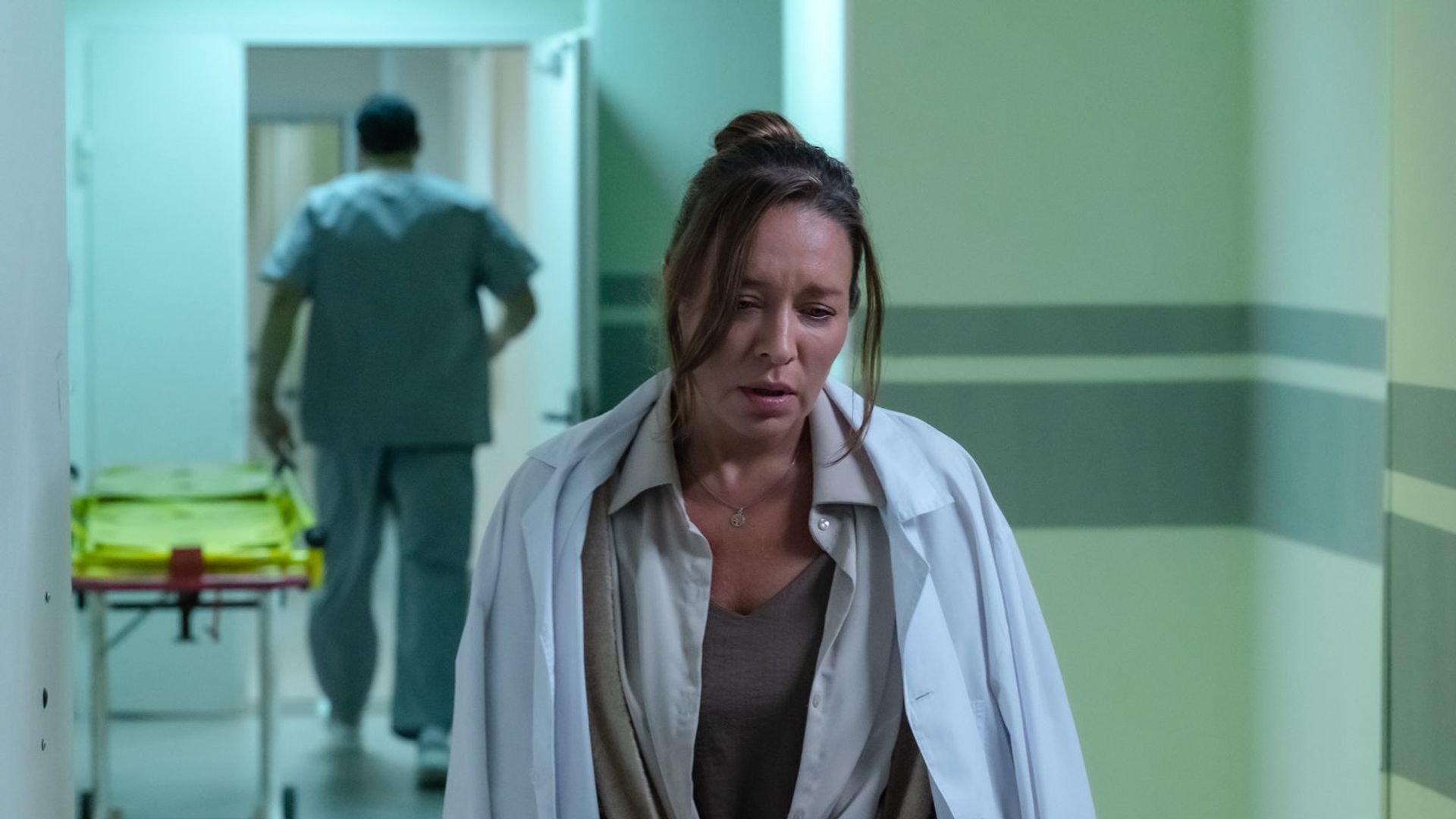 Серафима Низовская в белом халате с грустным лицом идет по коридору больницы