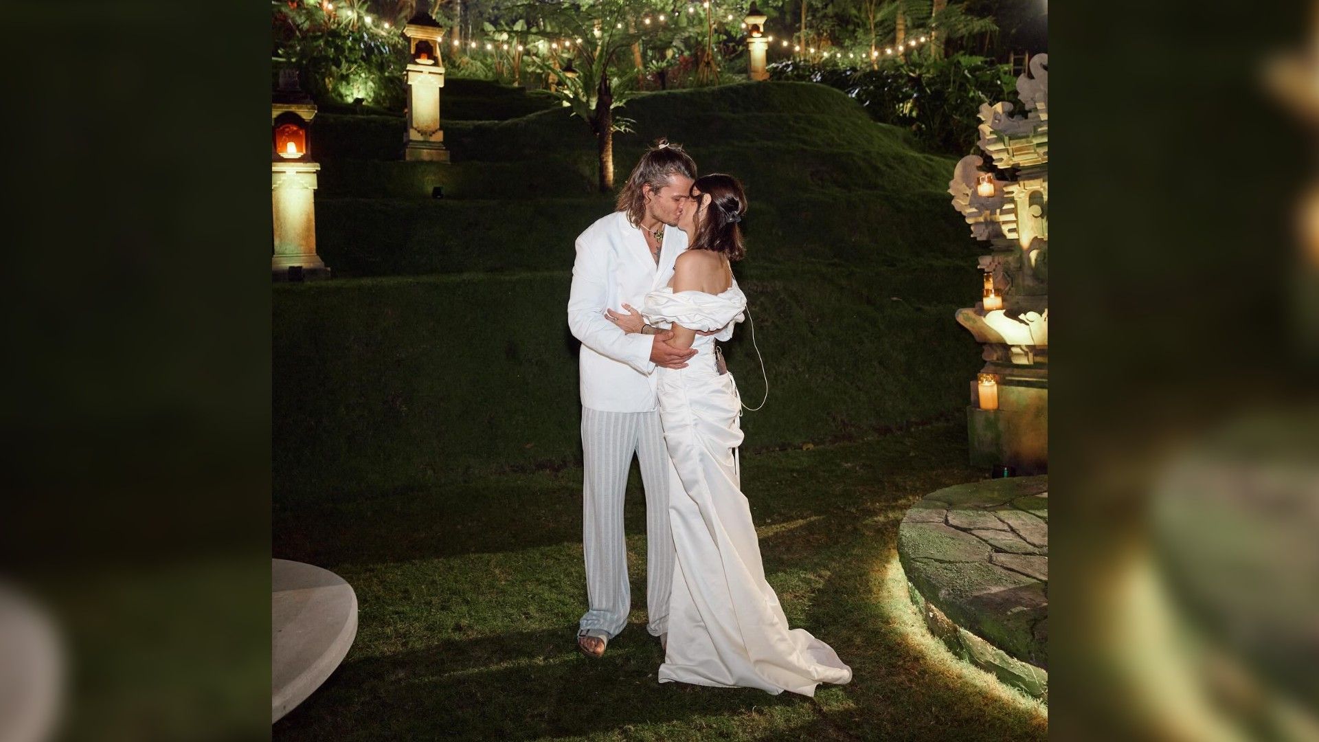 Айза и Степан Кузьменко целуются в белых нарядах, на фоне природа Бали