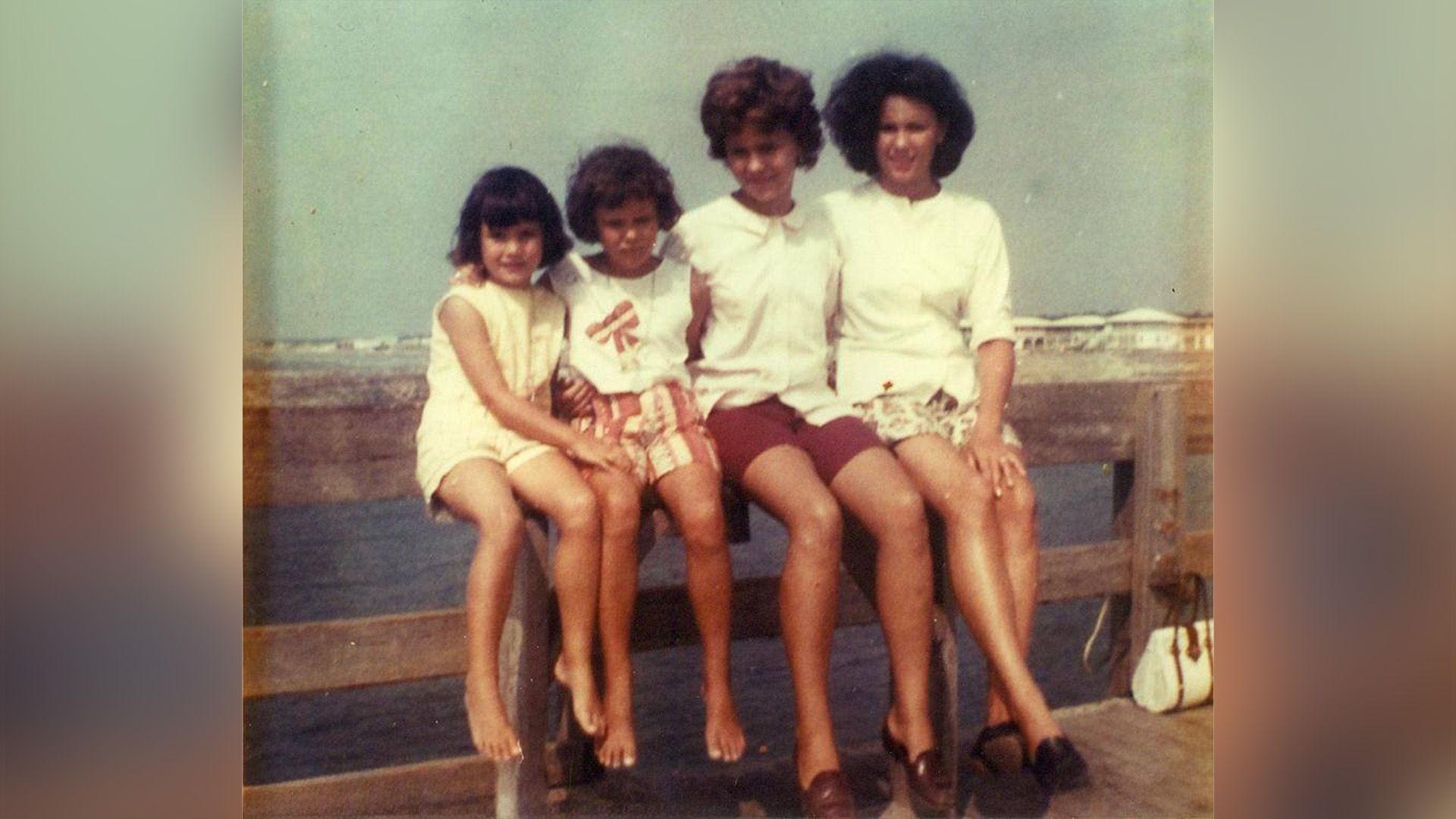 Энди МакДауэлл и три её сестры сидят на ограде деревянного пирса