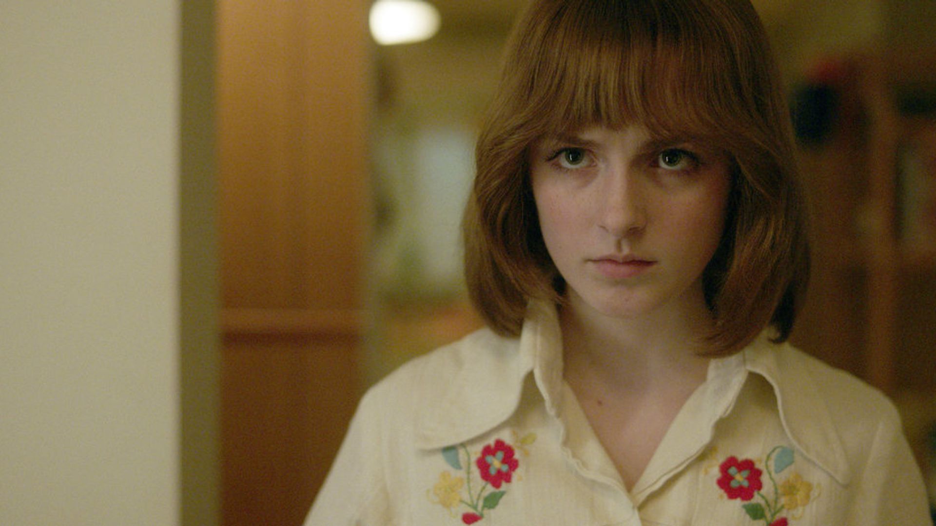 Маккена Грейс с рыжим каре и одеждой моды 80-х, кадр из мини-сериала