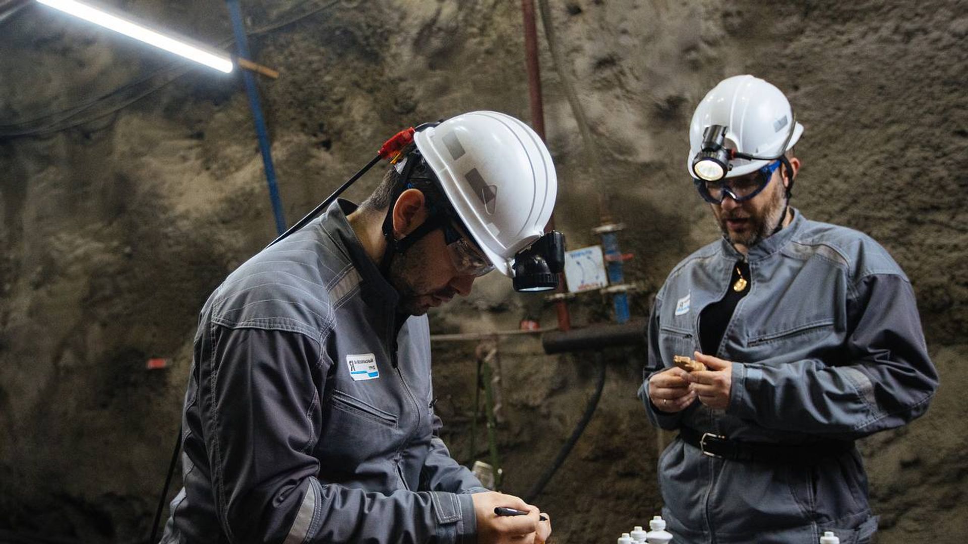 Александр Цыпкин и Ян Непомнящий в шахтёрских касках в шахте, рядом стоит шахматная доска