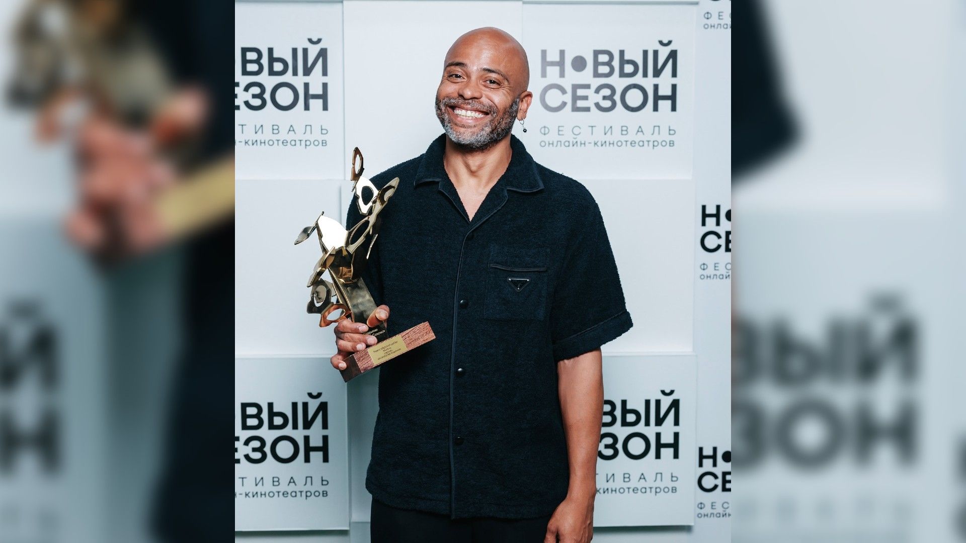 Мигель позирует перед камерами и держит в руках награду