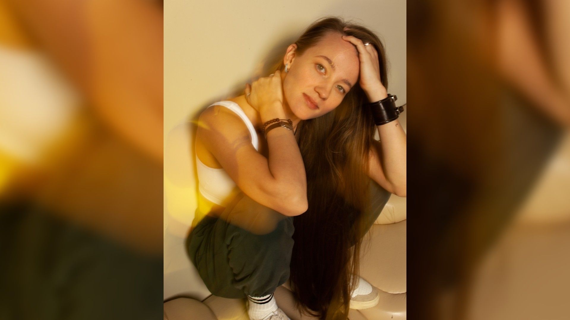 Виктория Плоп сидит на корточках, прислонившись к стене, солнечная атмосфера