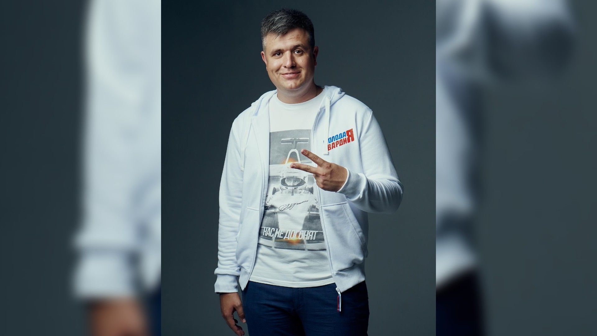 Александр Толмачёв в белом худи показывает жест победы