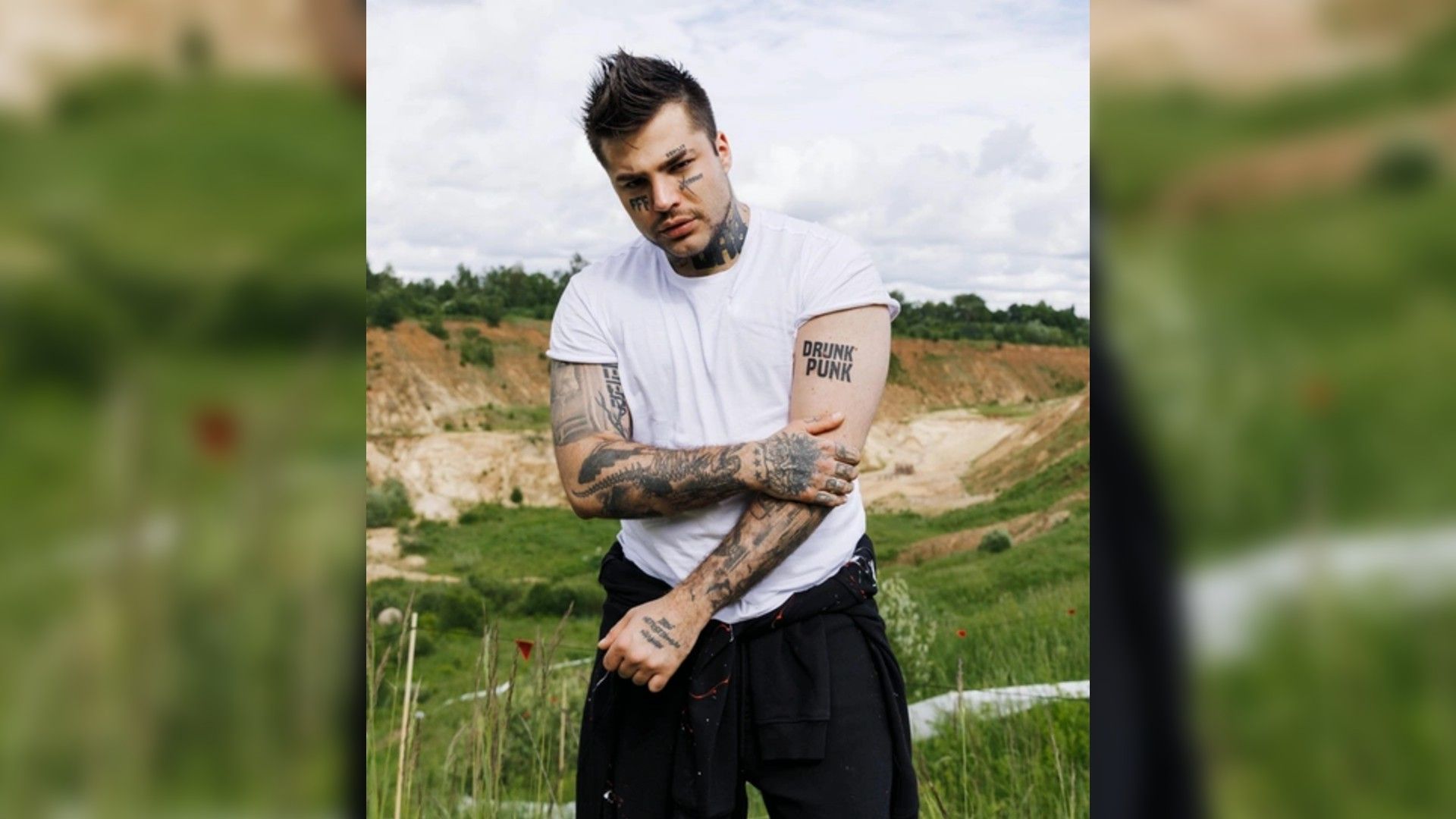 Рома Жёлудь в белой футболке в полный рост на открытом воздухе