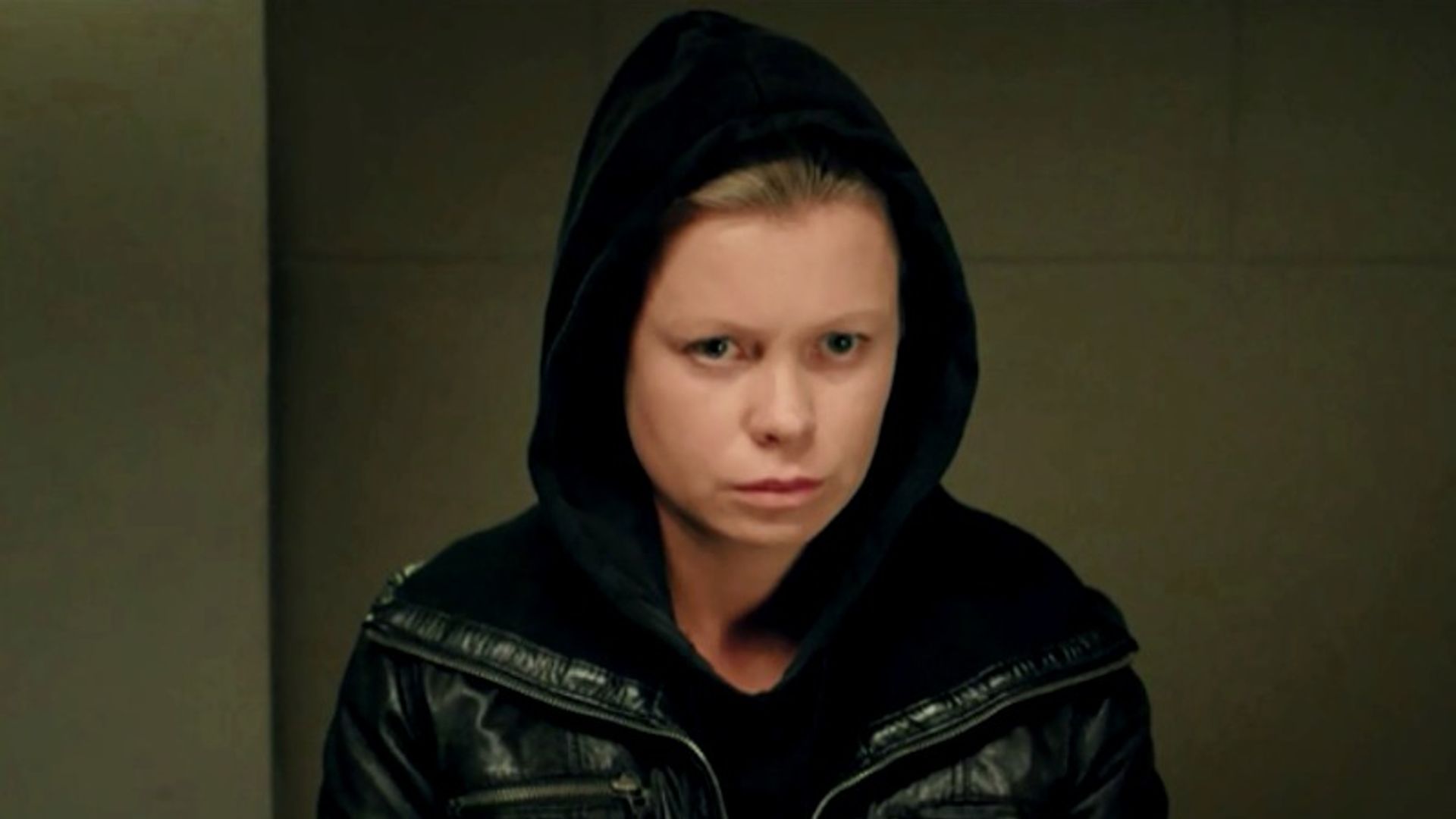 Евгения Осипова без макияжа в чёрном капюшоне на фоне стены