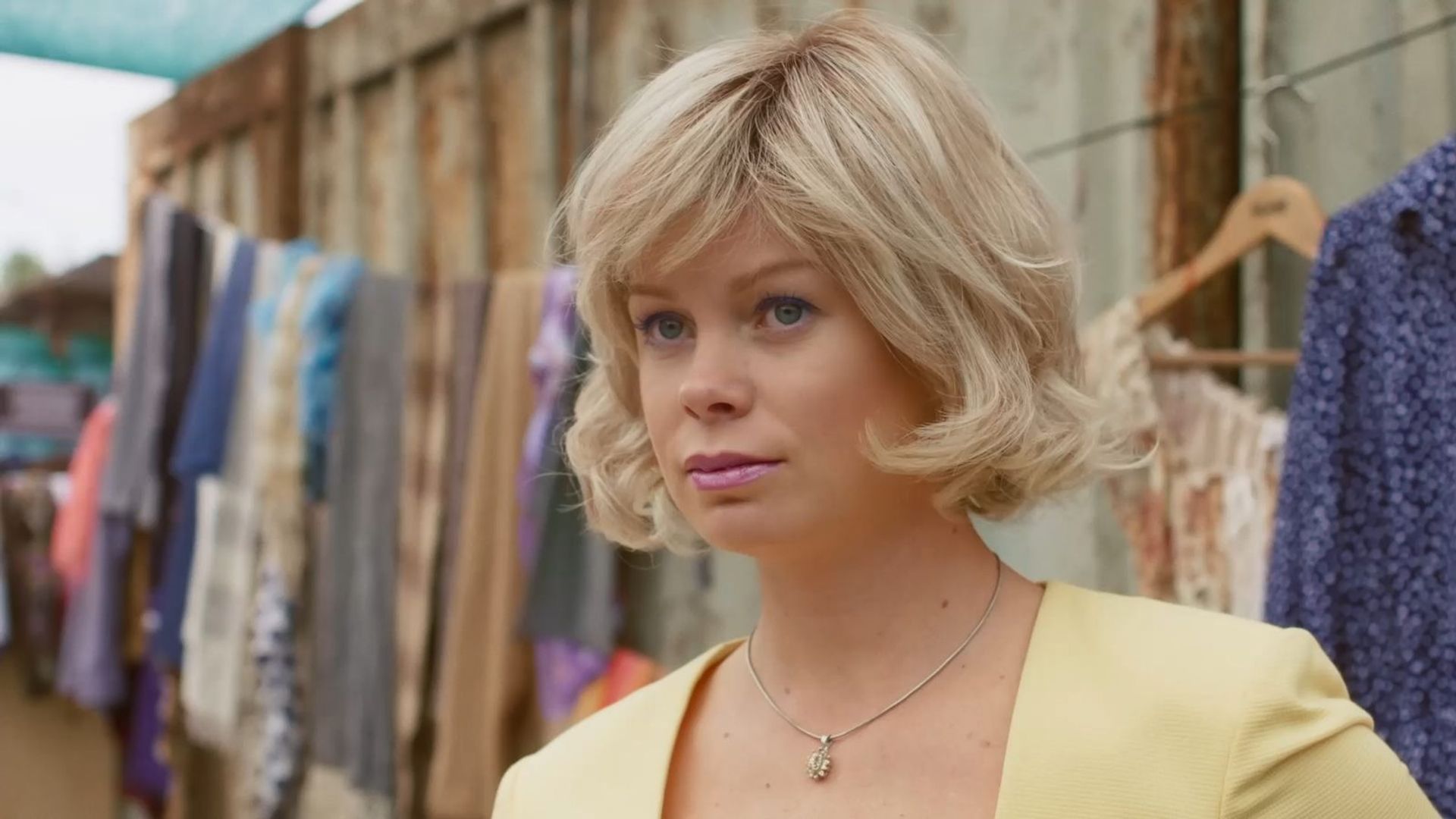 Евгения Осипова с короткой завивкой на фоне деревенской стены и развешенного белья