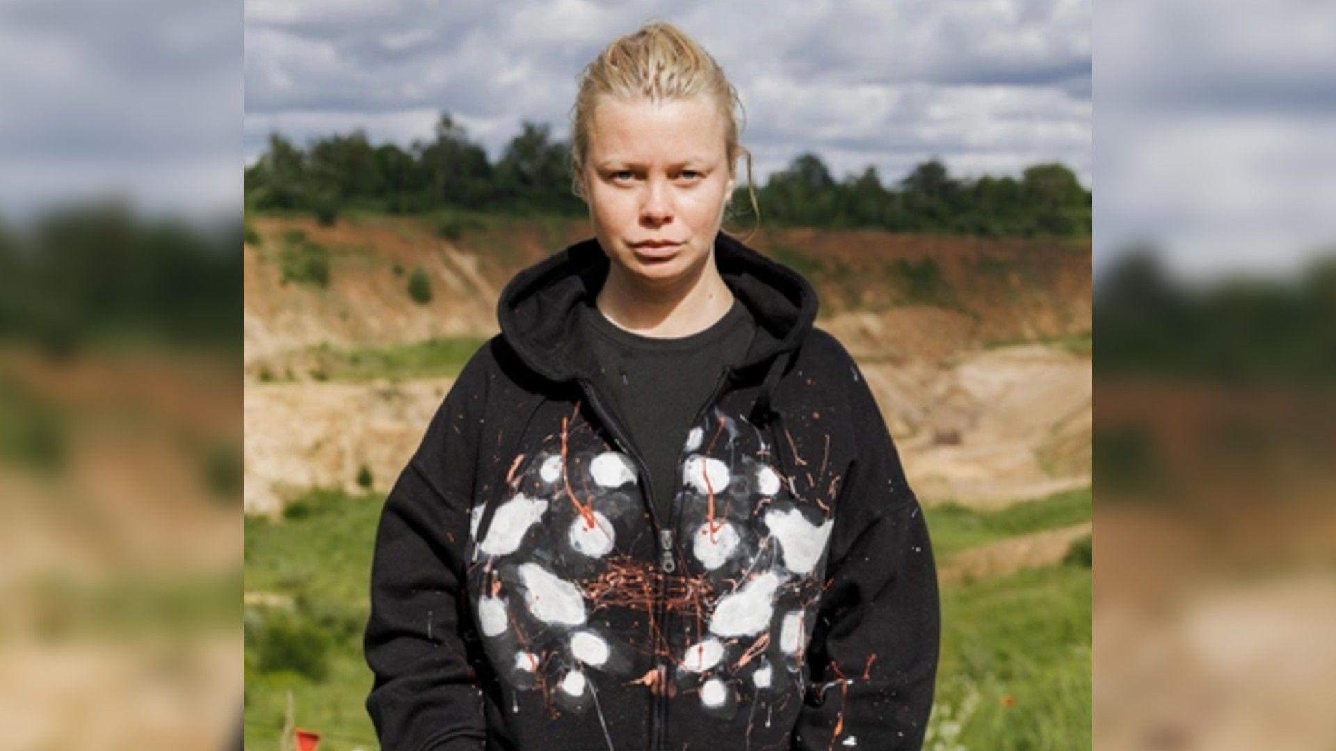 Евгения Осипова в чёрном худи на фоне природы