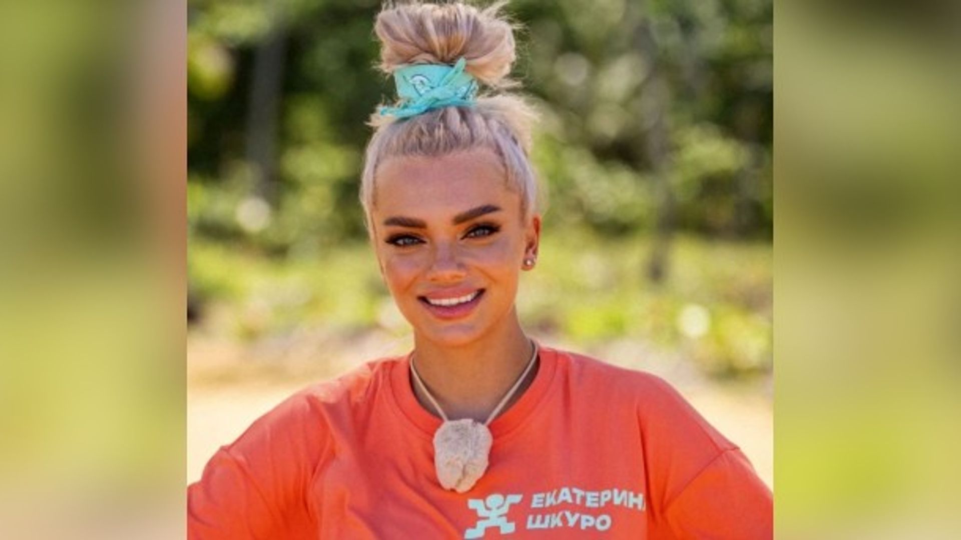 Екатерина Шкуро с высоким пучком волос и в оранжевой футболке улыбается