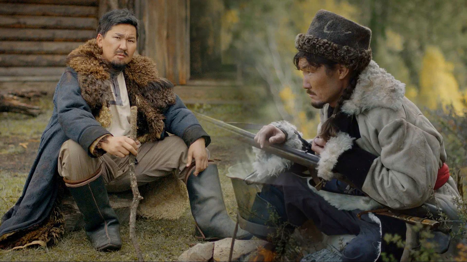 Двое мужчин сидят в народных одеждах на зеленой траве