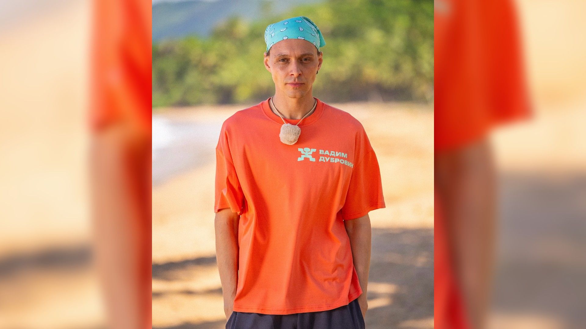 Вадим Дубровин в оранжевой футболке и голубой бандане на фоне побережья