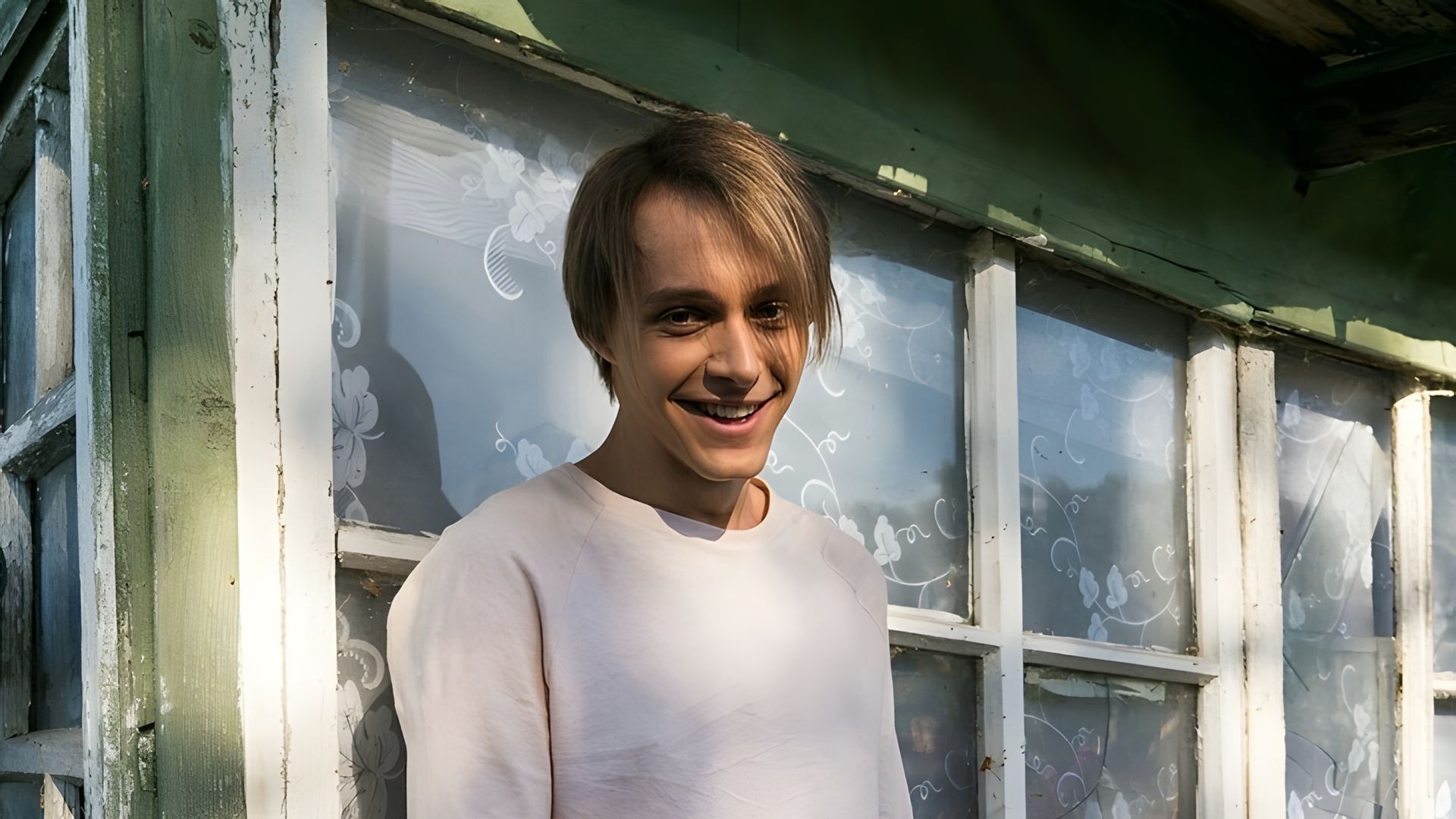 Вадим Дубровин улыбается в камеру, на фоне - фасад деревенского дома