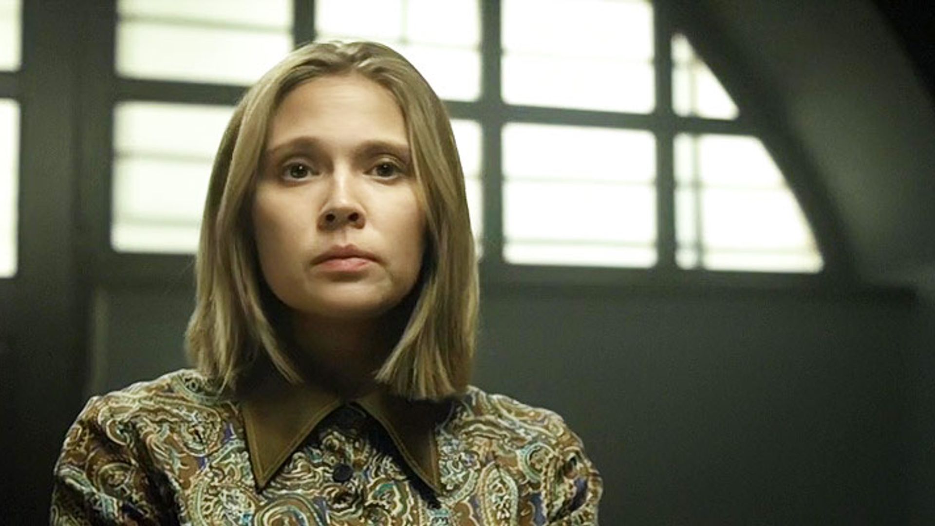 Виктория Романенко в платье с цветами смотрит в камеру со строгим выражением лица