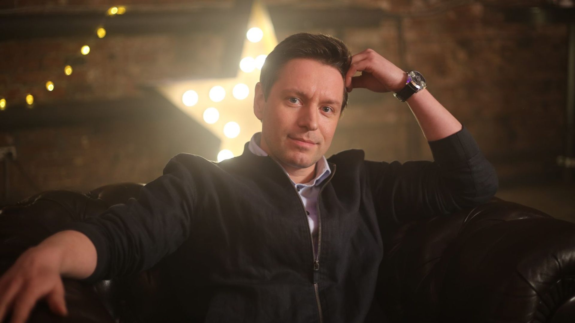 Владимир Жеребцов с лёгкой улыбкой сидит в расслабленной позе