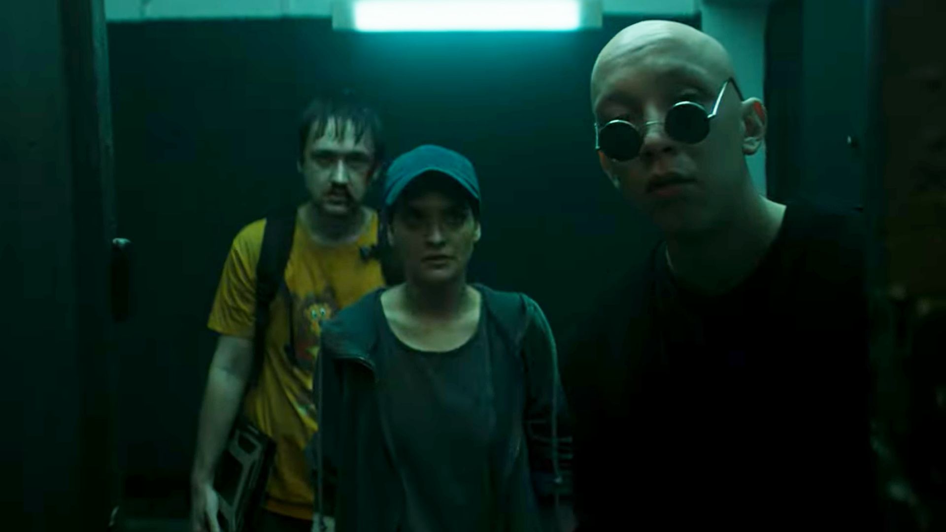 Актер Лев Зулькарнаев в круглых очках стоит рядом с девушкой и парнем