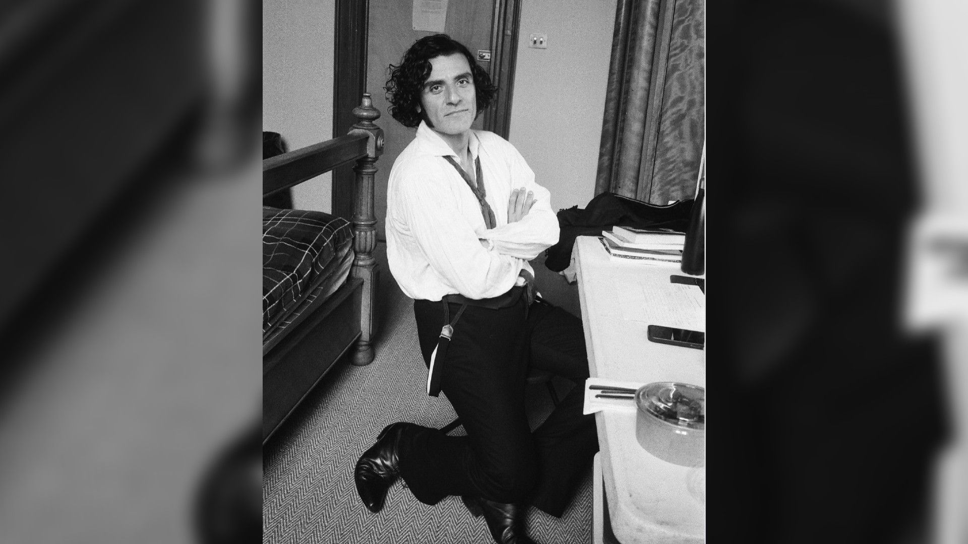 Оскар Айзек в рубашке и брюках сидит перед туалетным столиком, чёрно-белое фото