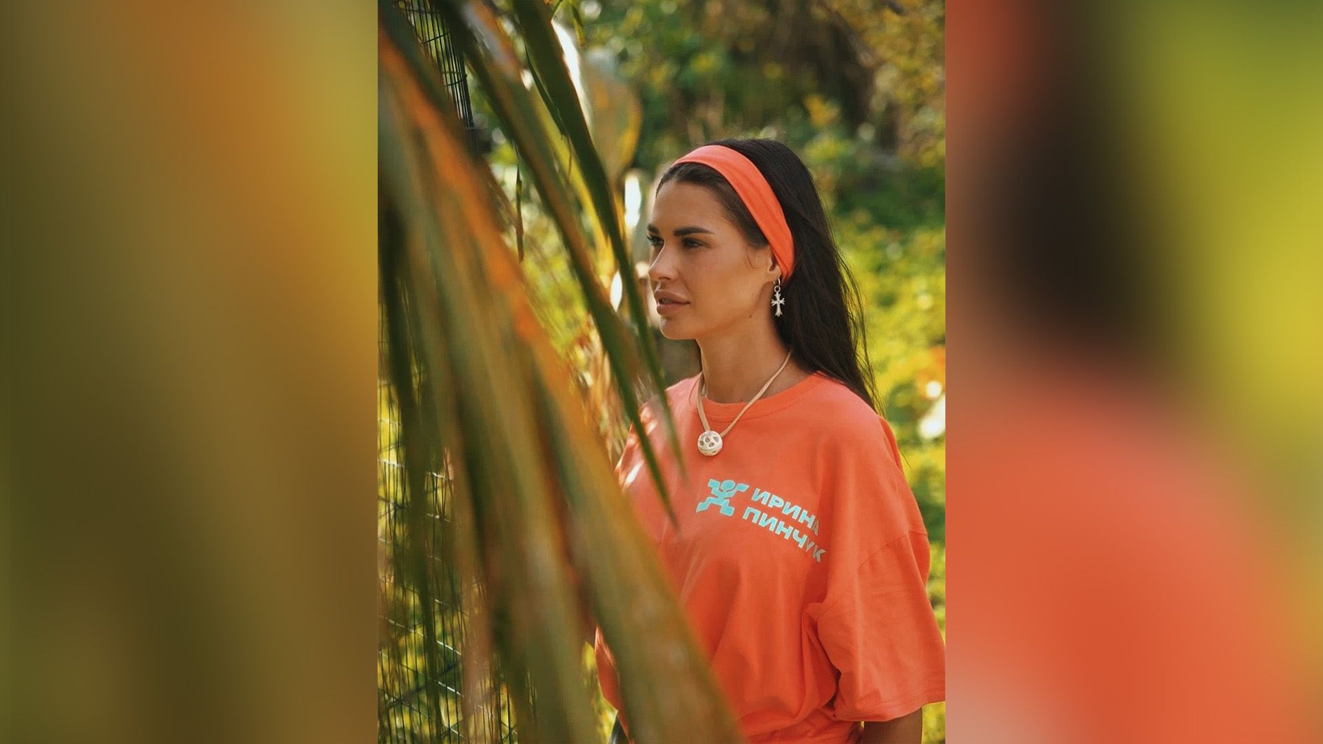 Ирина Пинчук в оранжевой футболке стоит среди пальм