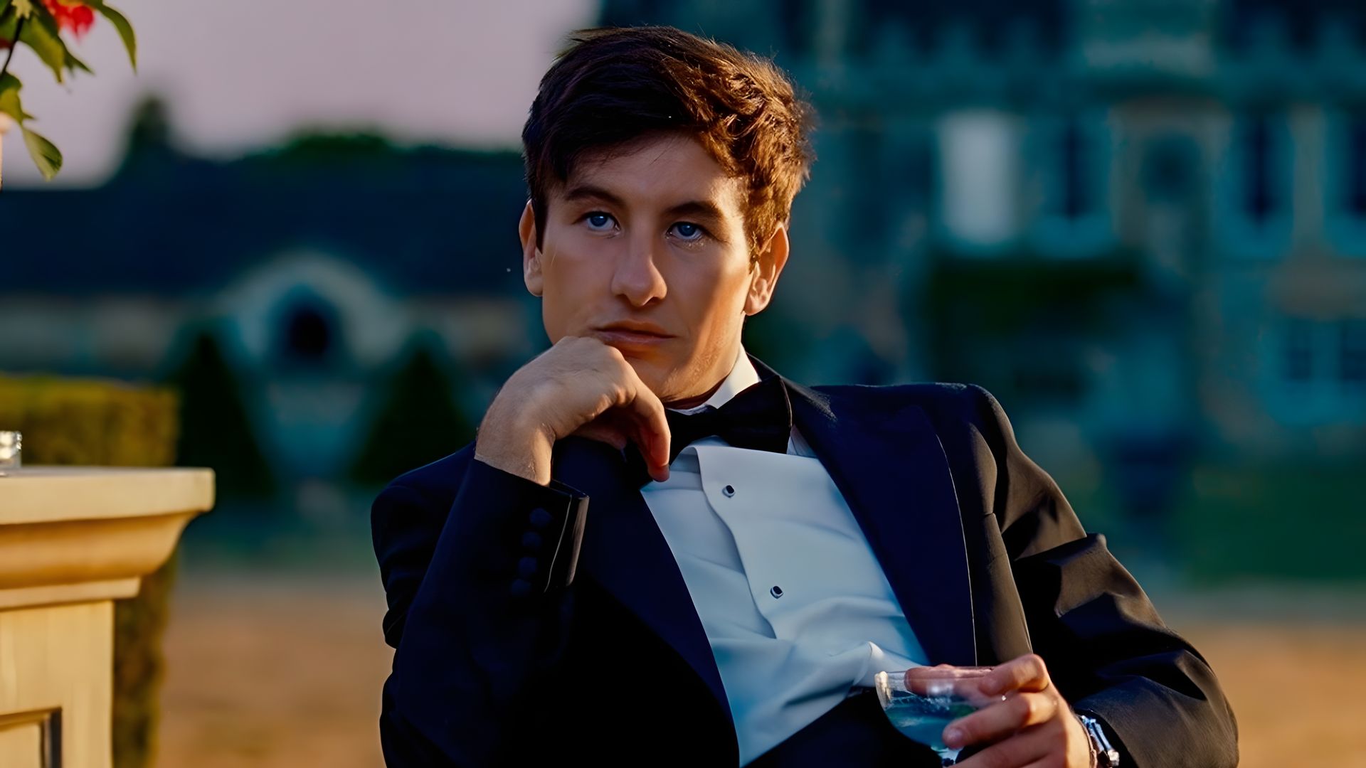 Барри Кеоган в смокинге сидит на улице с бокалом в руке