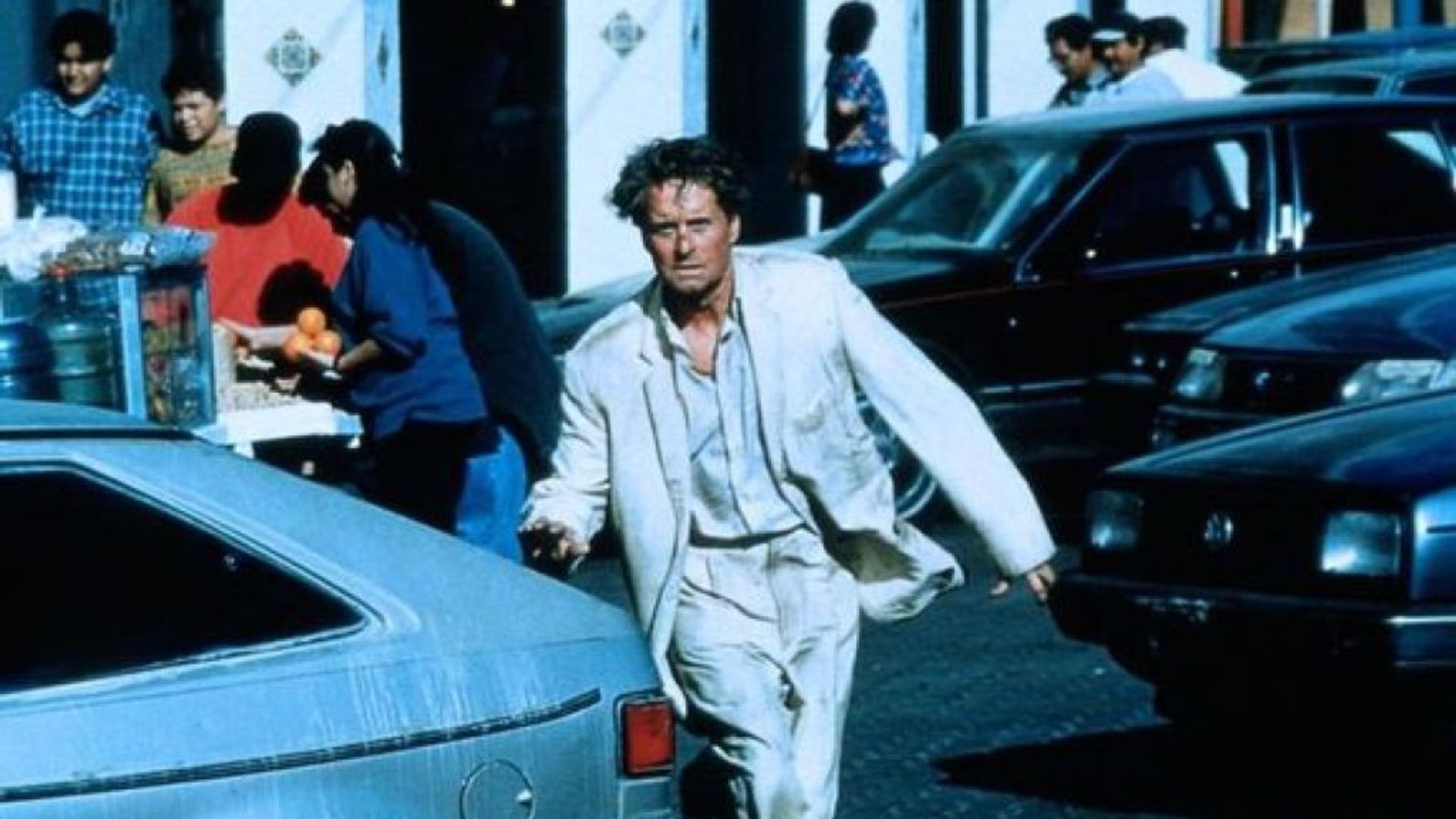 Растрёпанный Майкл Дуглас в белом пиджаке бежит по улице