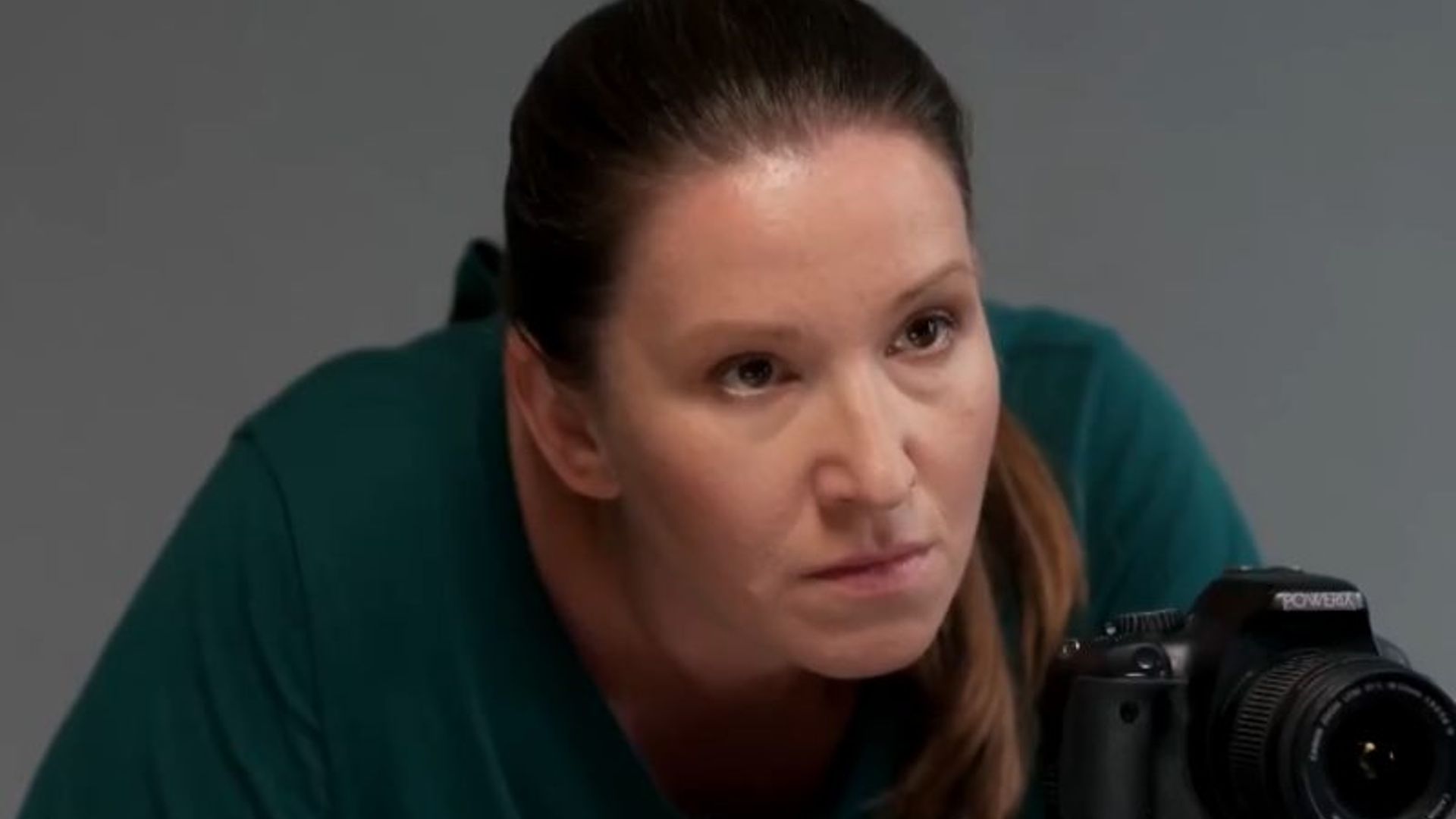 Елена Муравьёва в зелёном свитере наклоняется к фотокамере