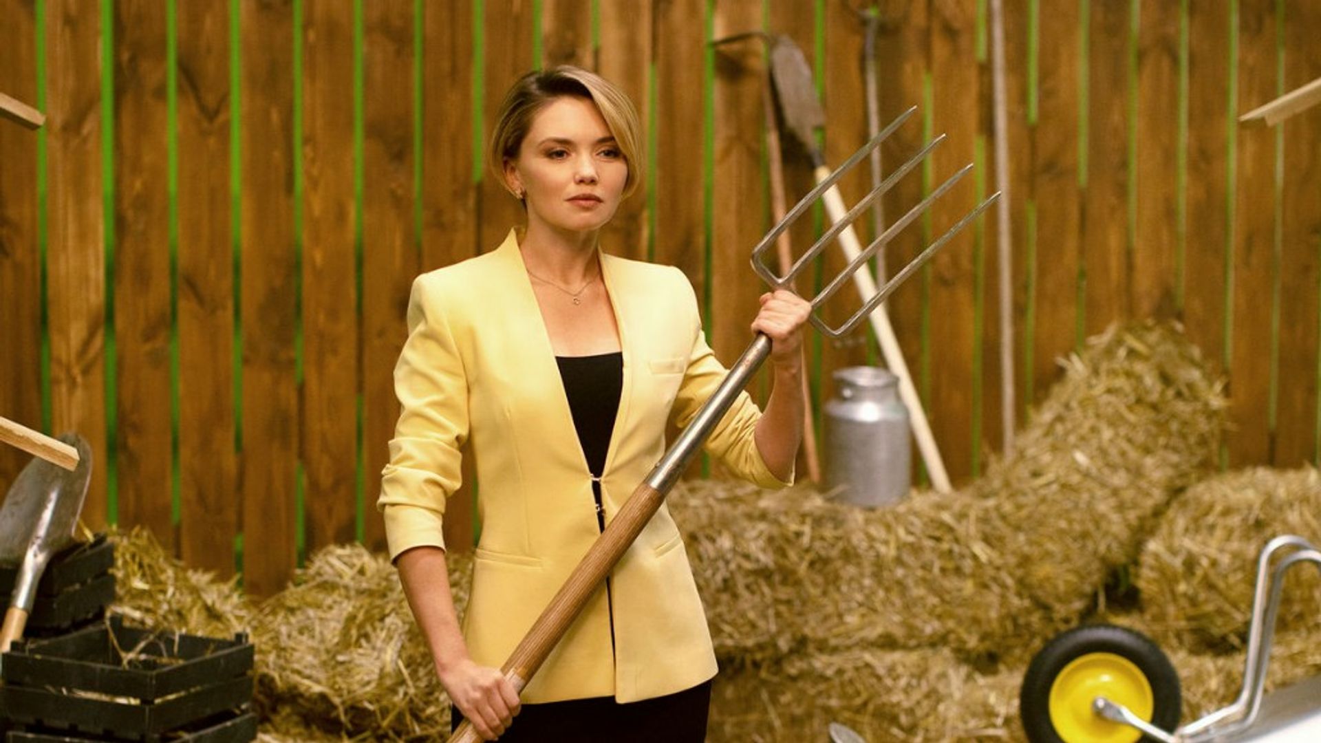Ольга Кузьмина в жёлтом пиджаке держит видлы на фоне амбара с сеном
