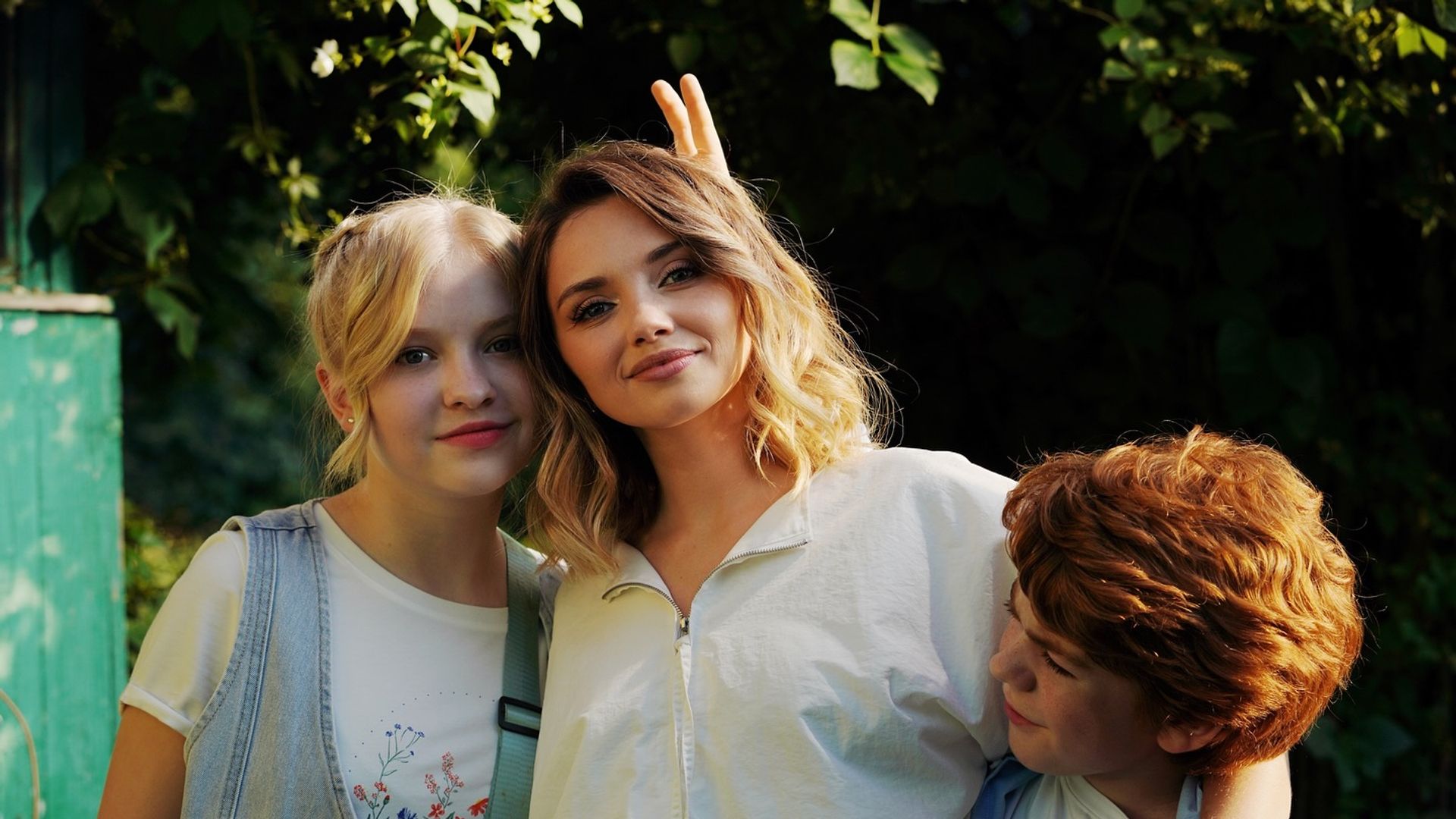 Ольга Кузьмина в окружении двоих детей позирует на фоне зелени