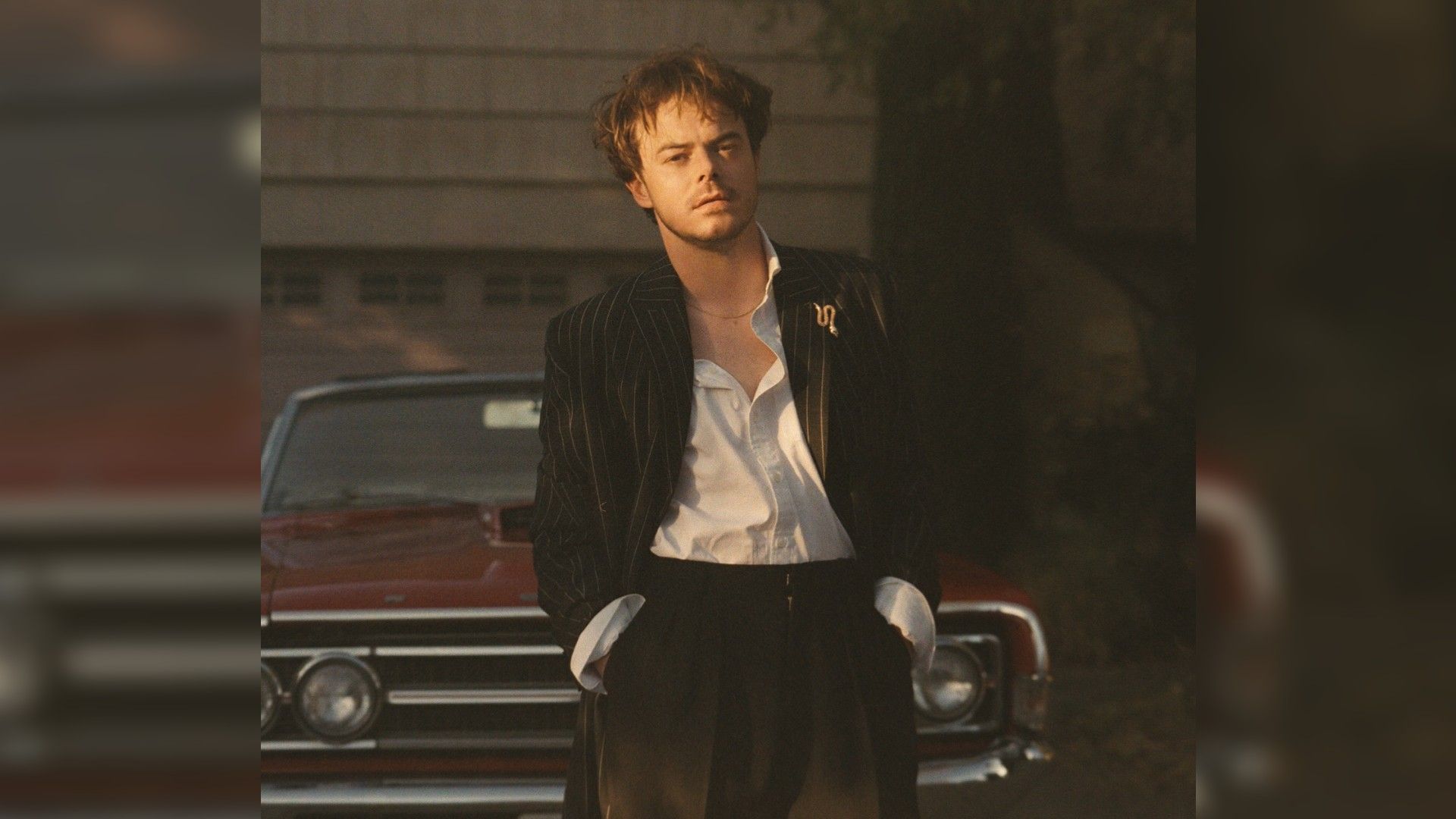 Чарли Хитон в костюме идёт по двору