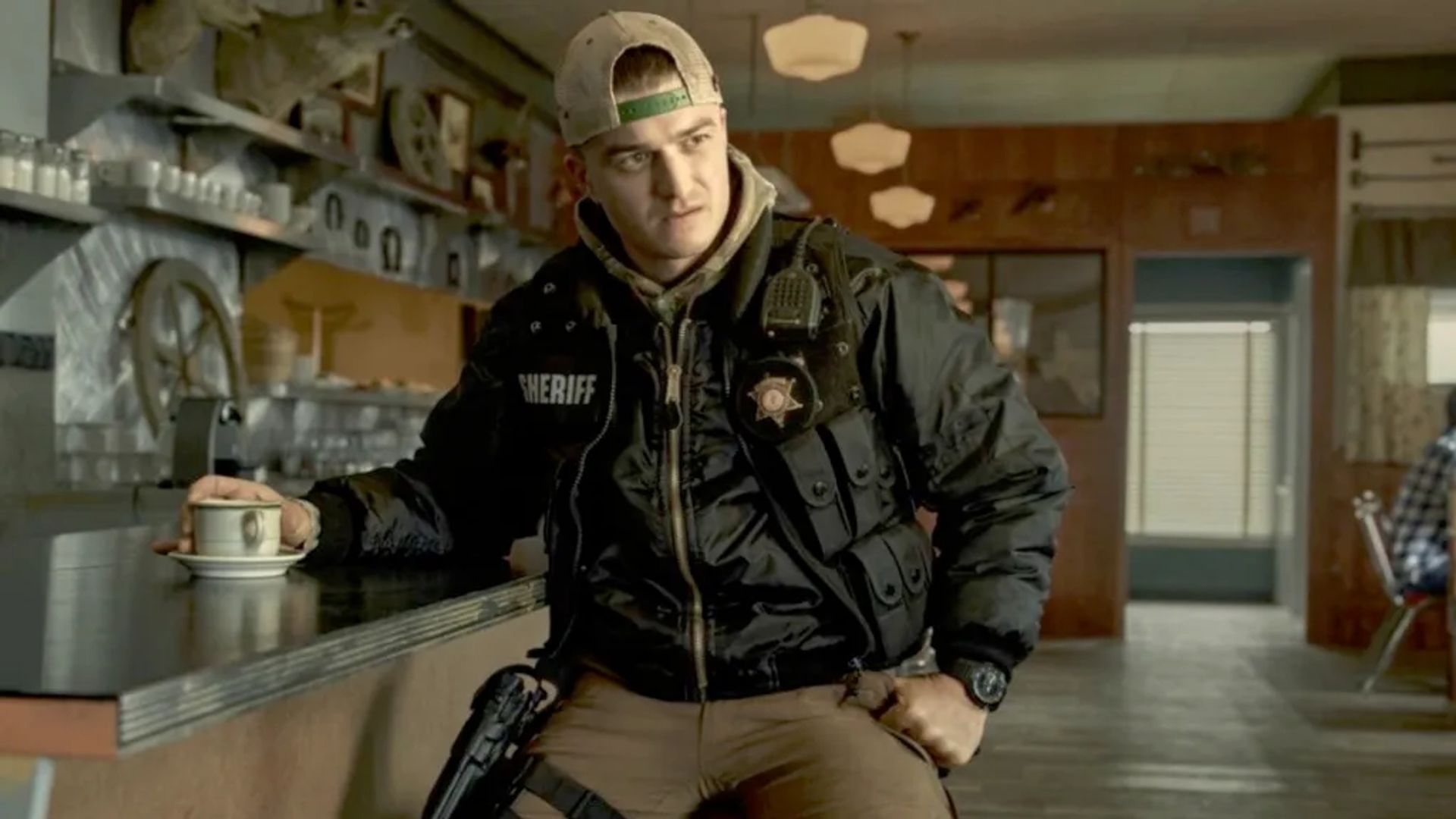 Джо Кири в форме шерифа сидит в баре