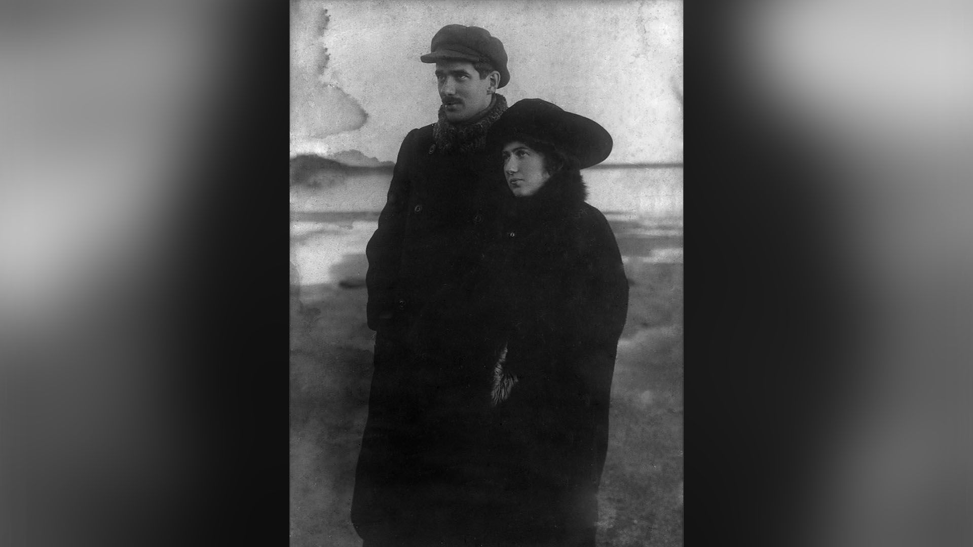 Корней Чуковский в пальто и кепке и его жена Мария стоят на берегу