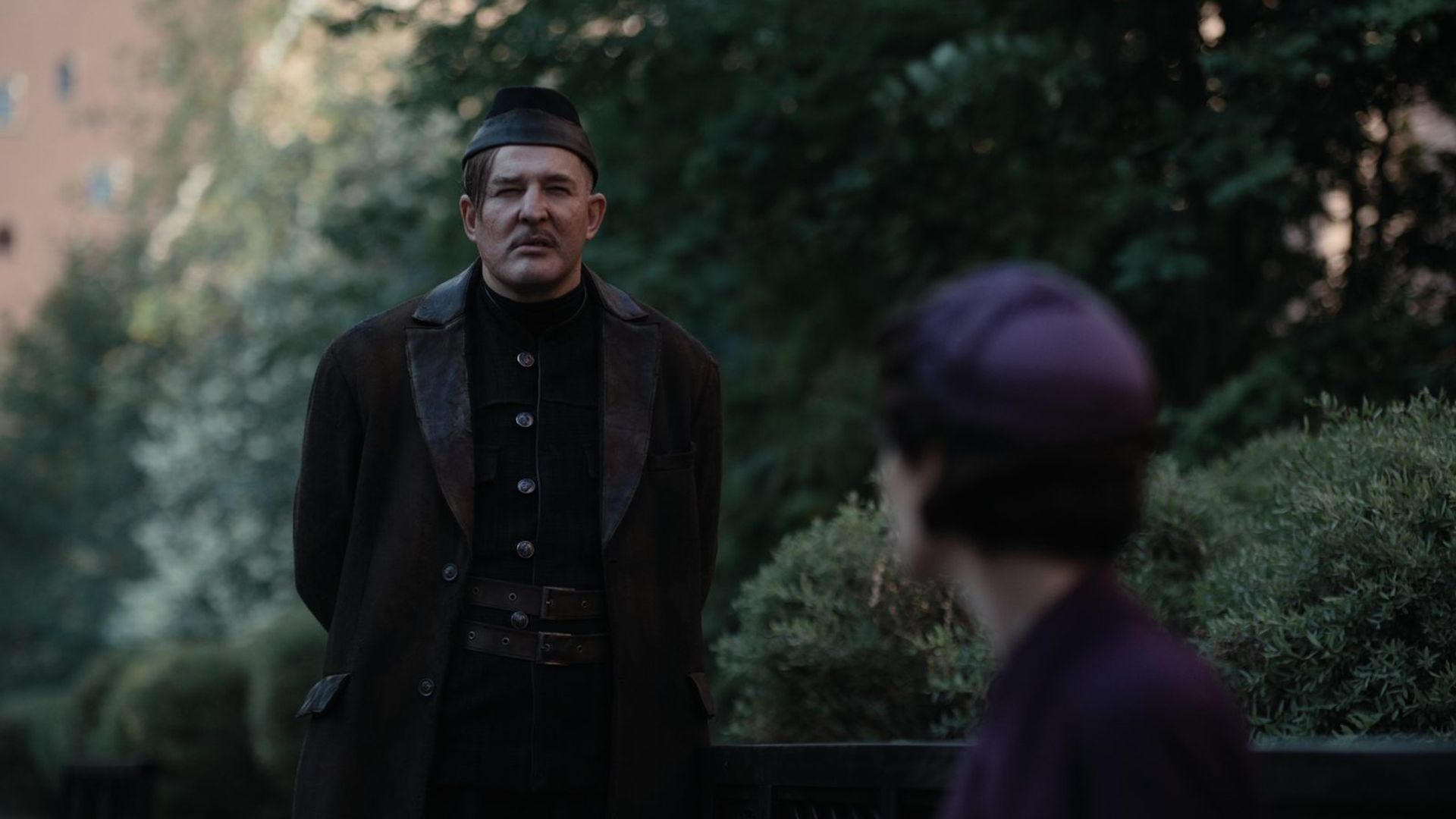 Алексей Розин в чёрном костюме и ермолке стоит на фоне парка