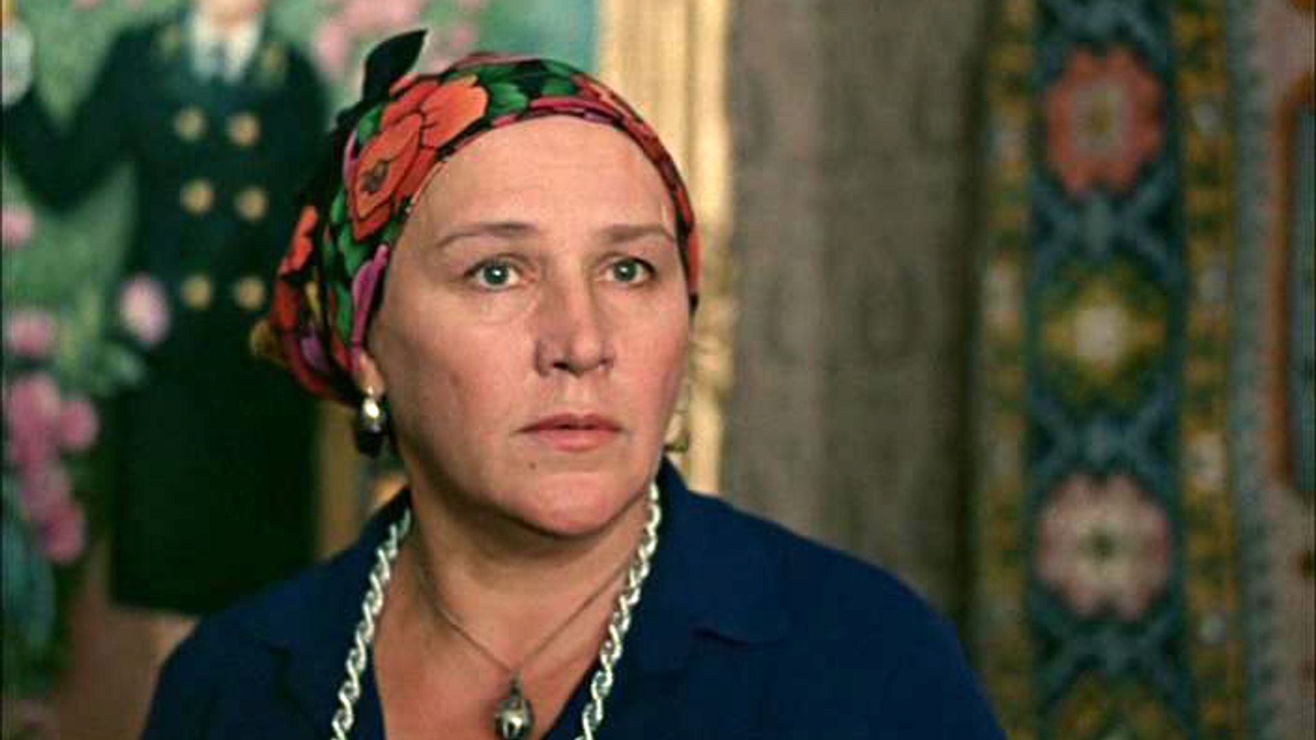 Нонна Мордюкова в цветной косынке на фоне гобелена