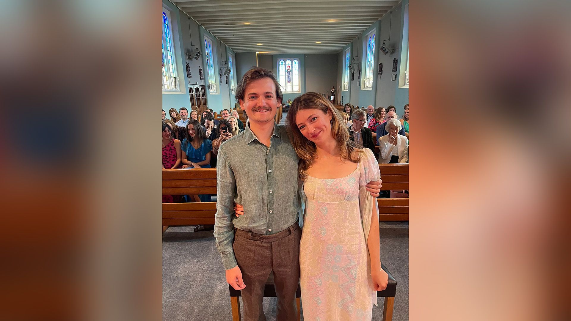 Джек Глисон и Ройшин О'Махони стоят в церкви, позади на скамьях сидят гости