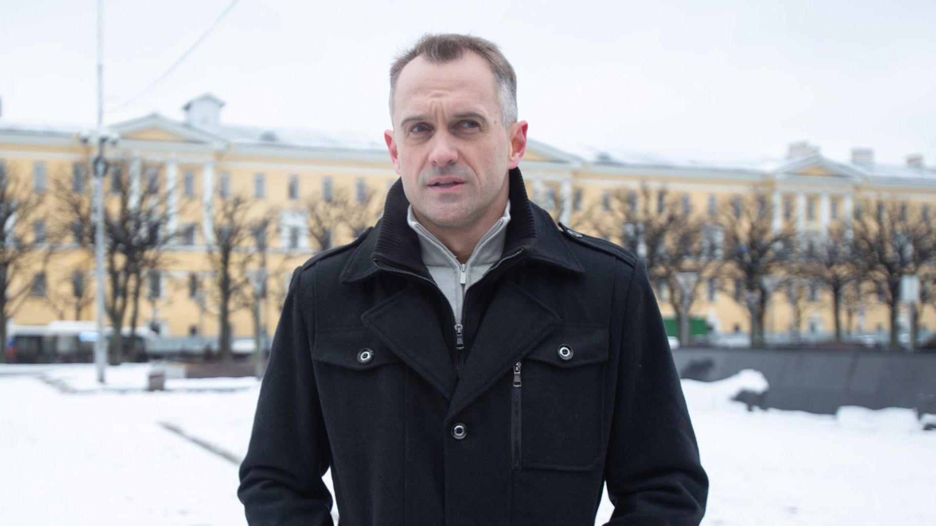 Алексей Комашко в черном палто стоит на зимней улице