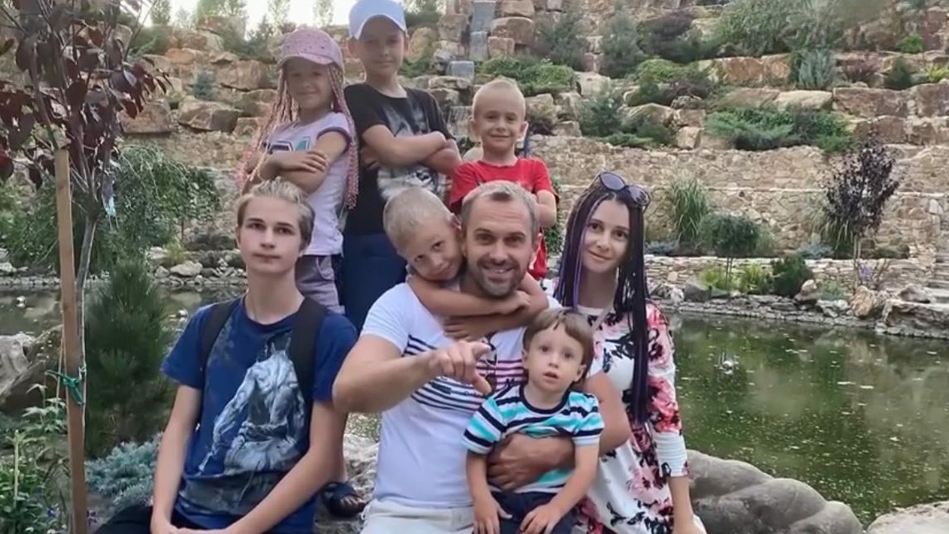 Алексей Комашко, его жена Галина и их шестеро детей позируют на фоне реки и скал