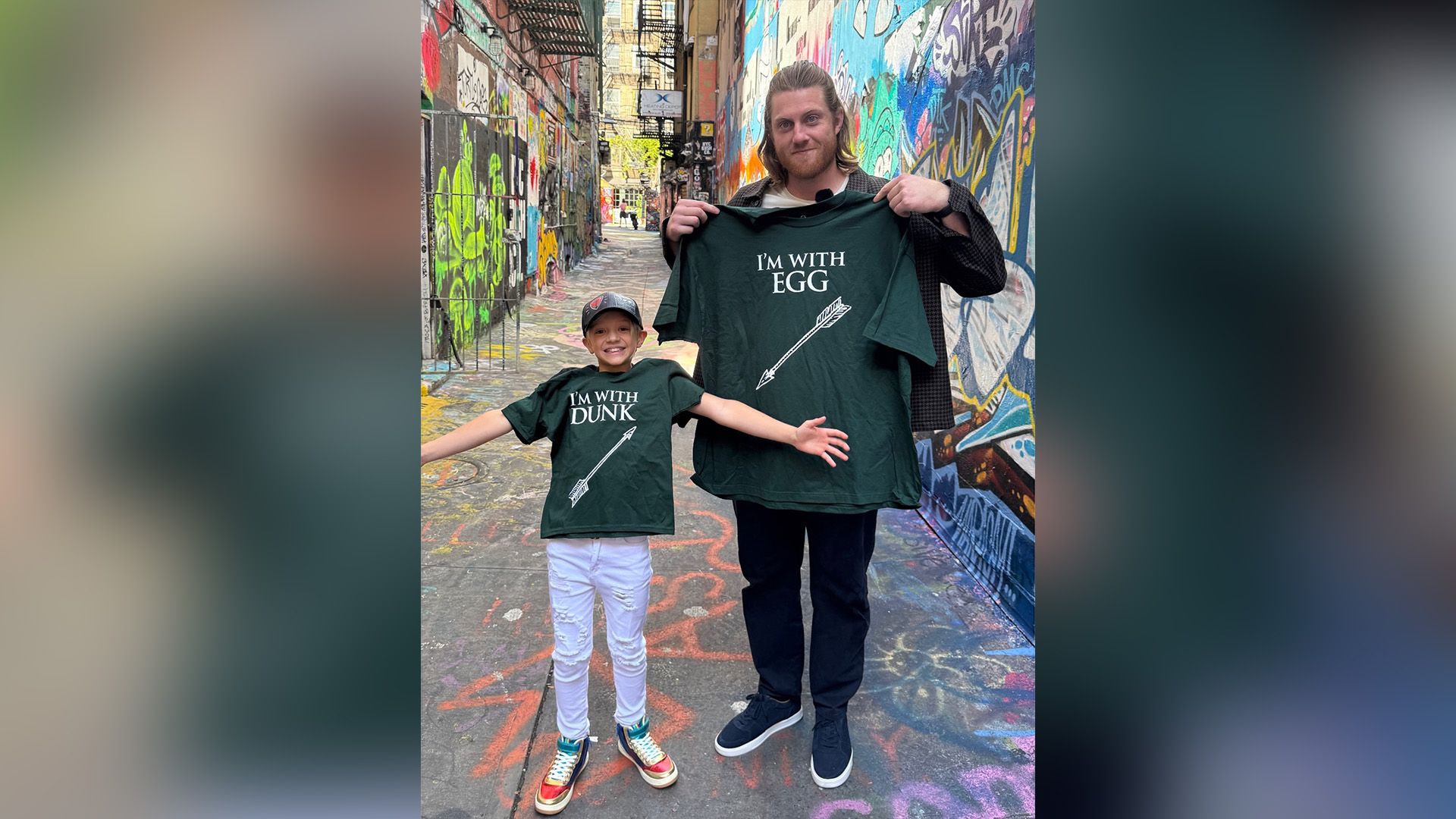 Питер Клэффи и Декстер Сол Анселл в парных зеленых футболках позируют на узкой улочке